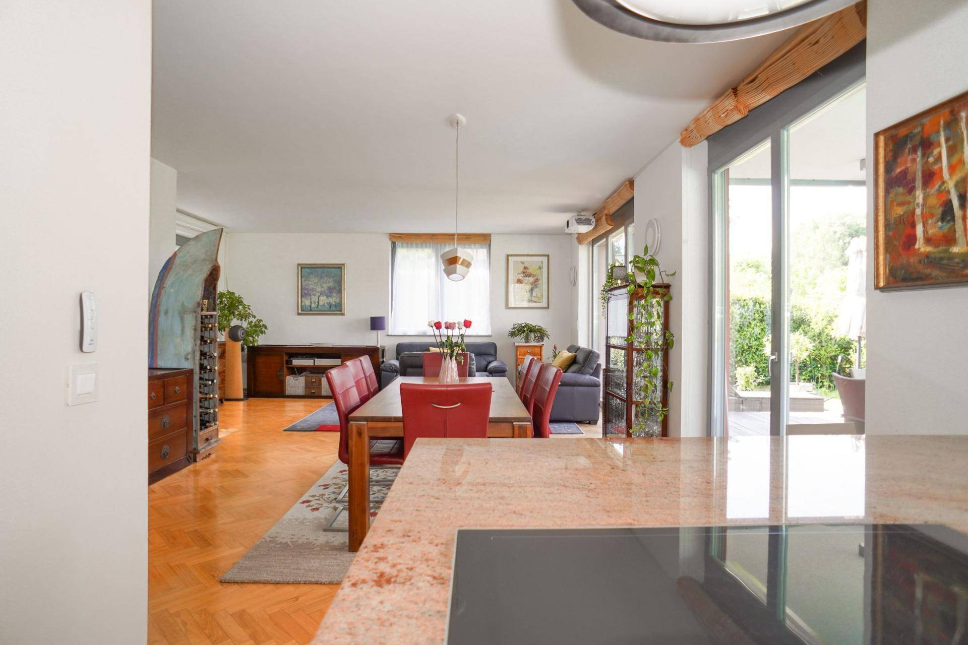 Blick von der Küche in den offenen Wohn-Essbereich mit Parkettboden und Terrassenzugang.