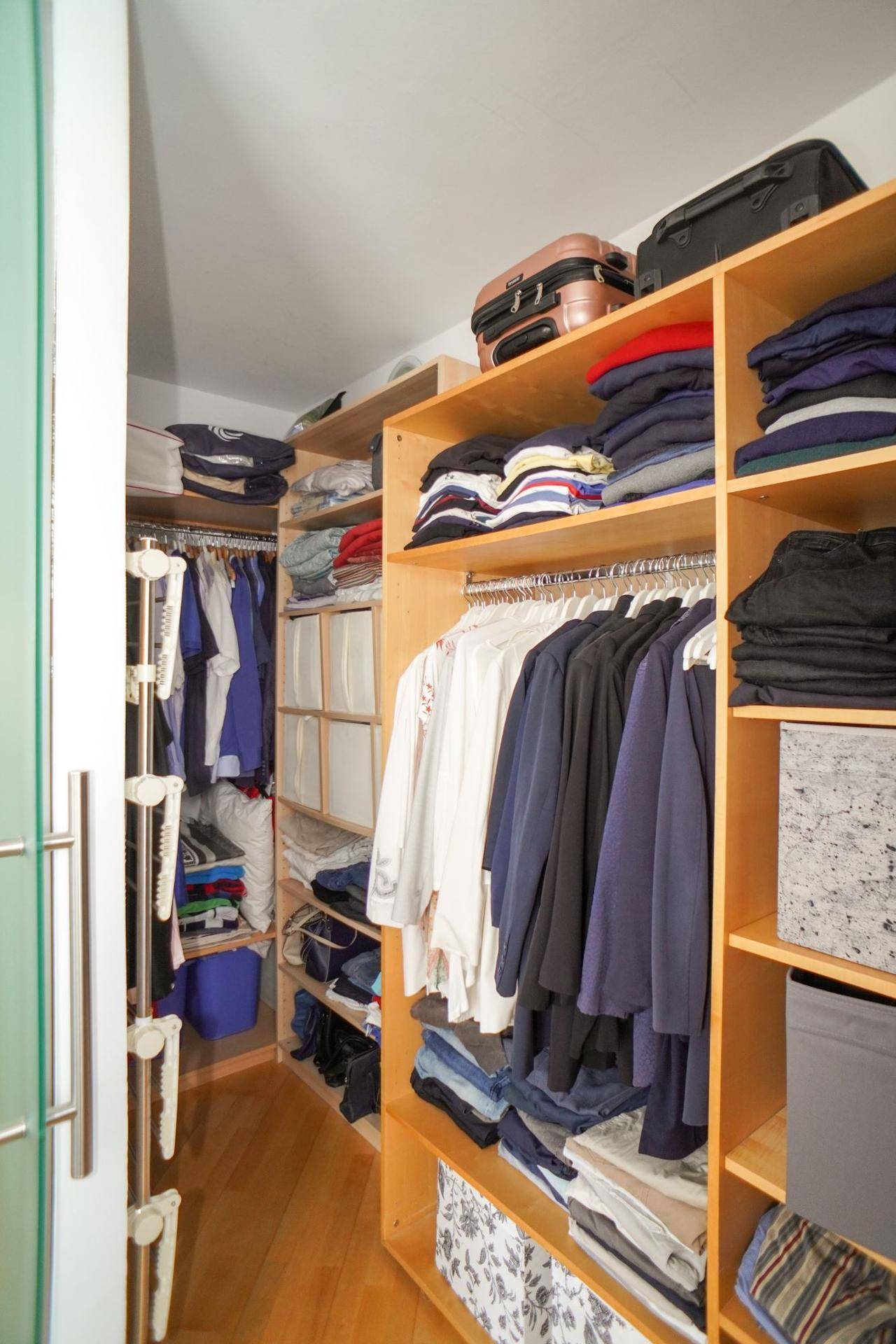 Geräumiger begehbarer Kleiderschrank mit vielen Regalen und Aufbewahrungsmöglichkeiten.