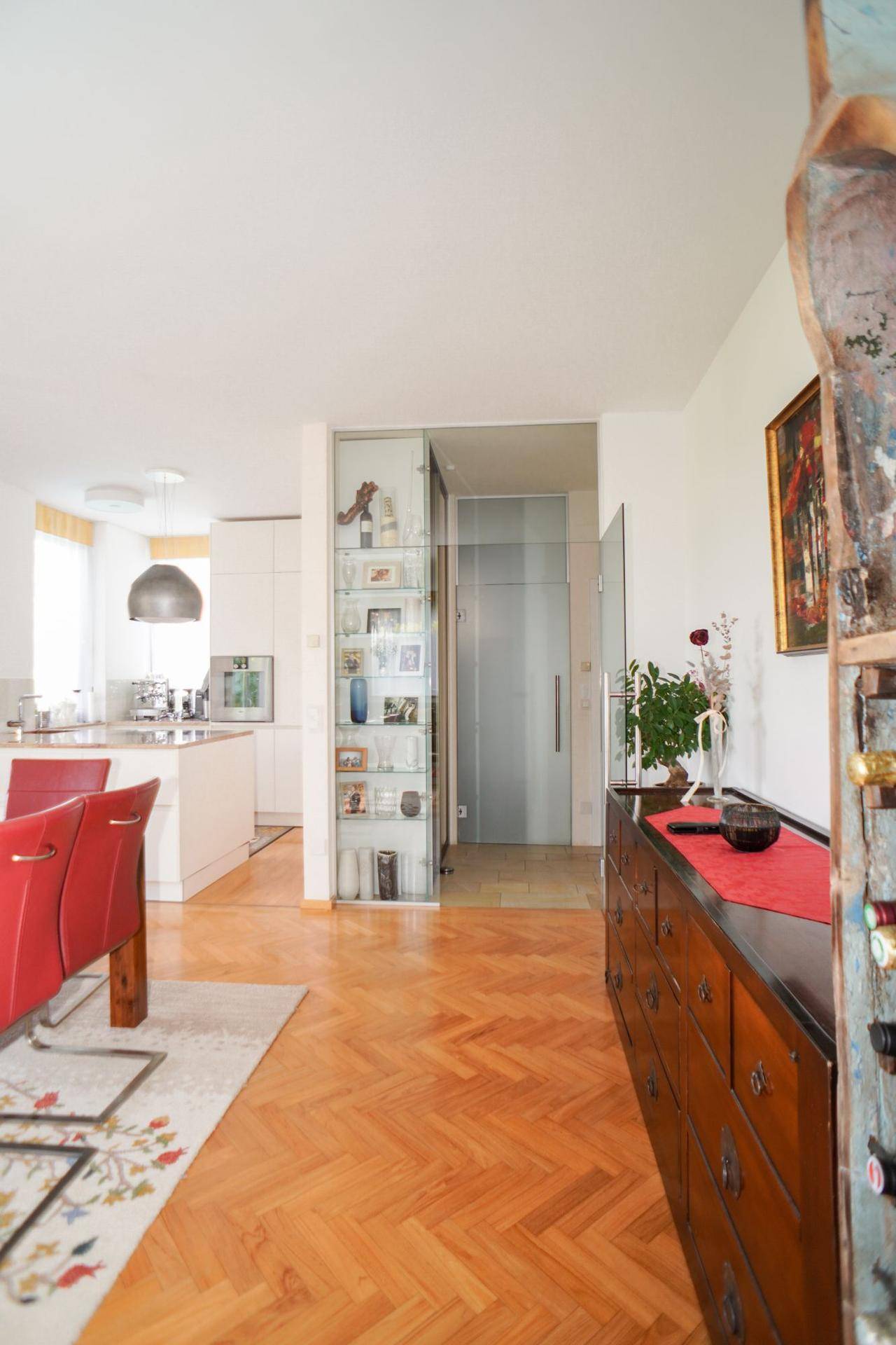 Heller Flur mit Parkettboden, Glasvitrine und Zugang zu den Wohnbereichen.