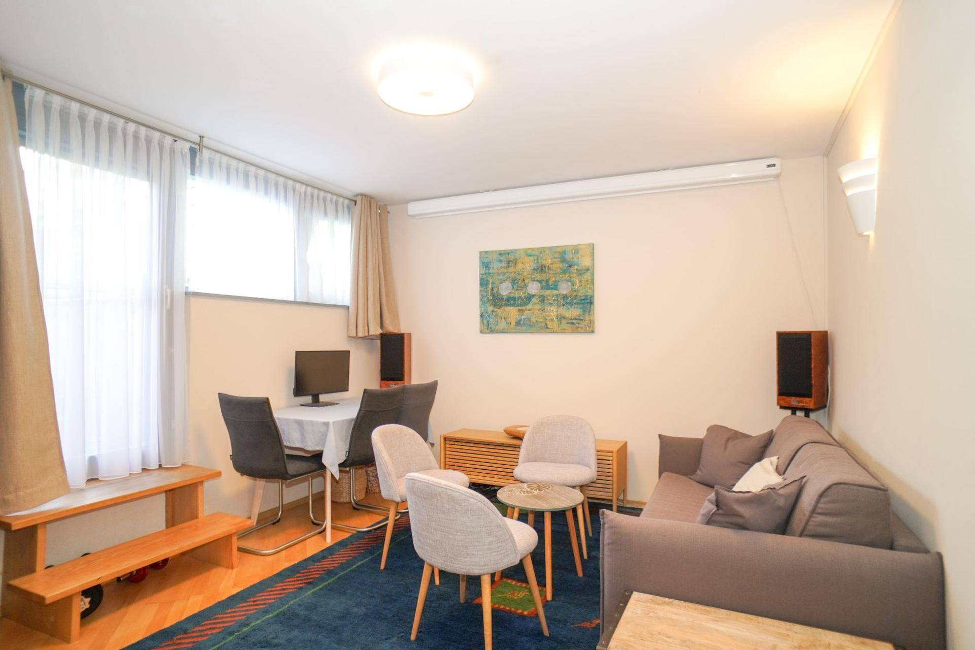 Gemütlicher Wohnbereich im Untergeschoss mit Sofa, Esstisch und Fenstern.