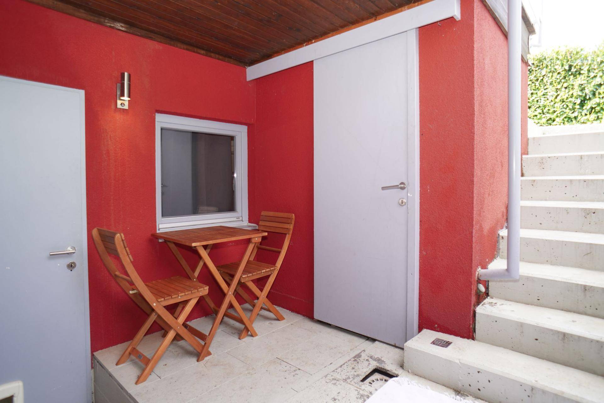 Kleiner überdachter Terrassenbereich mit Holztisch und Stühlen, direkt am Haus.