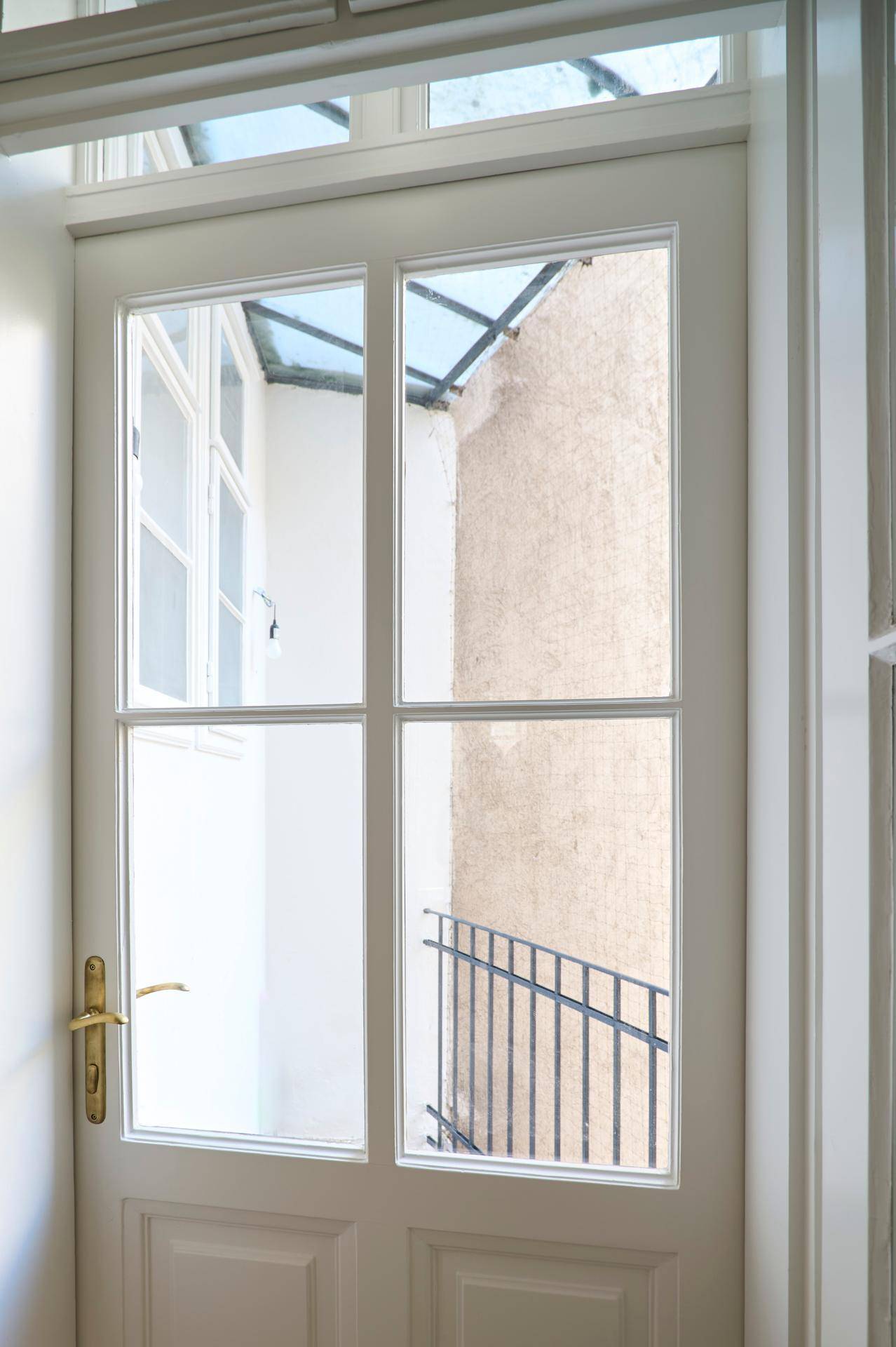 Eine Glastür führt zu einem Innenhof mit Treppe, der natürliches Licht in den Eingangsbereich bringt.