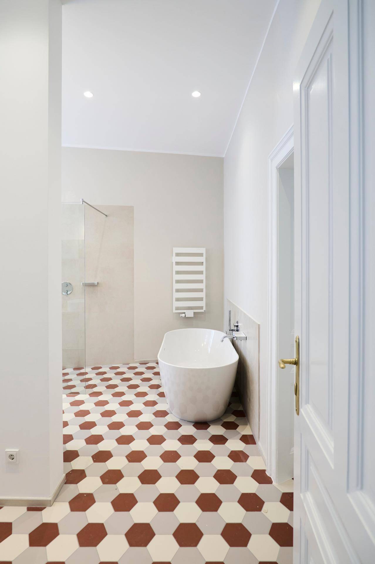 Modernes Badezimmer mit freistehender Badewanne, begehbarer Dusche und auffälligem sechseckigem Fliesenboden.