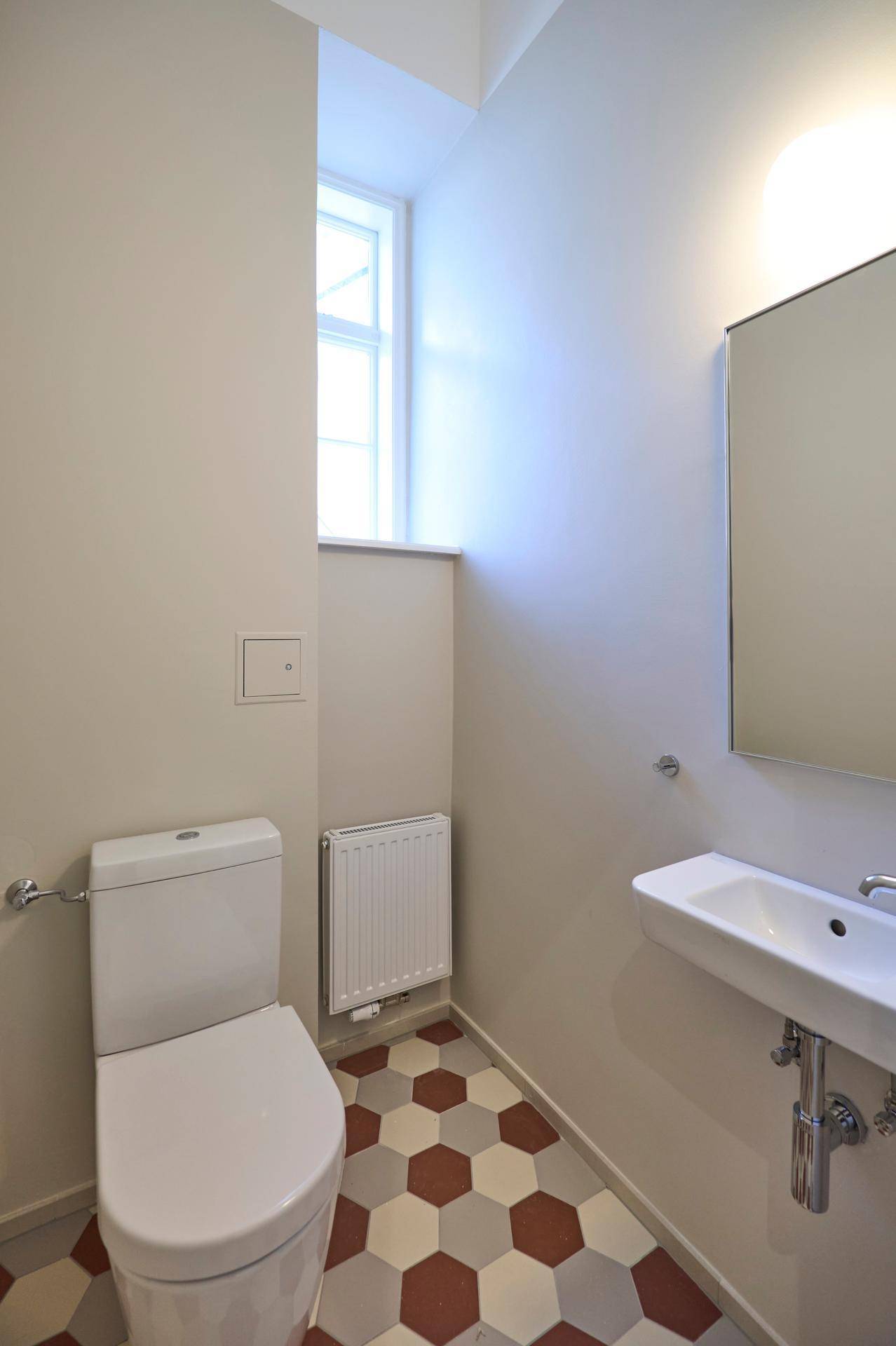 Kleines Gäste-WC mit modernem Waschbecken, wandhängender Toilette und sechseckigem Fliesenboden.