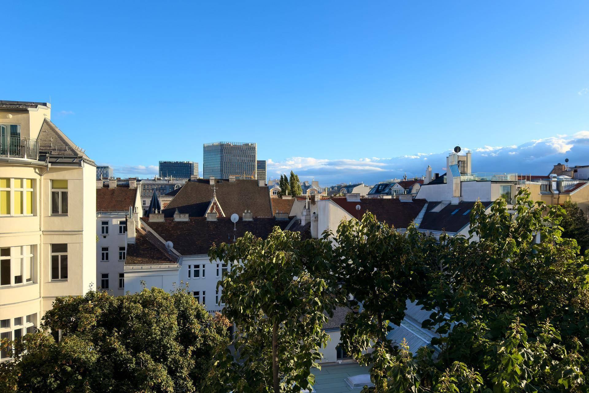 Panoramablick über die Dächer der Stadt mit historischer und moderner Architektur unter blauem Himmel.