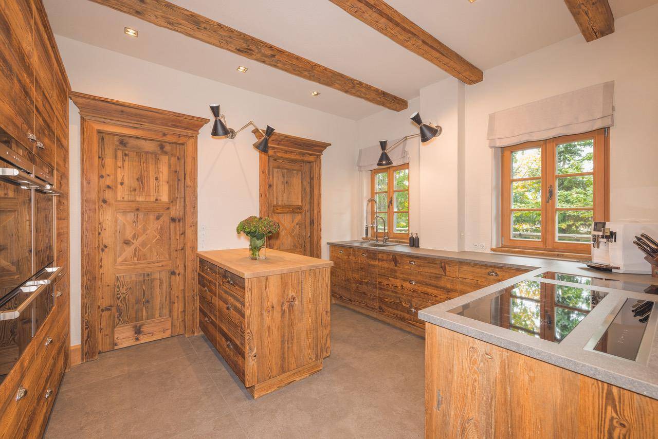 Moderne Holzküche mit Kochinsel, Stein-Arbeitsplatten und integrierten Geräten.