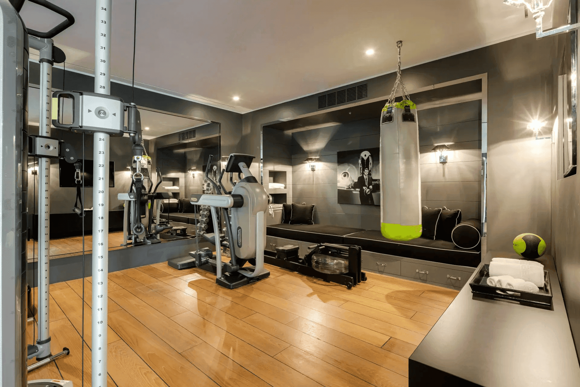 Gut ausgestatteter Fitnessraum mit verschiedenen Trainingsgeräten und Boxsack.