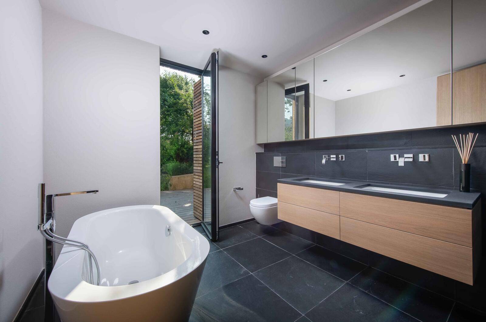 Modernes Badezimmer mit freistehender Badewanne, Doppelwaschbecken und Zugang zum Garten.