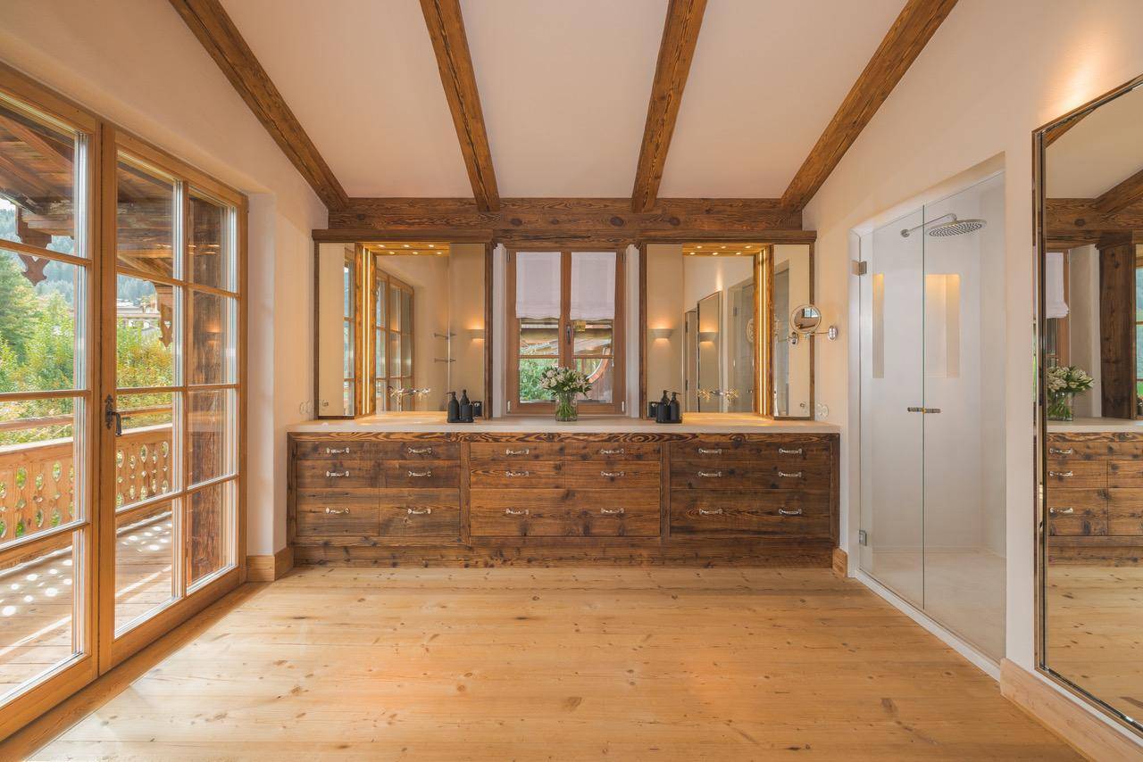 Helles Badezimmer mit Doppelwaschtisch, Glasdusche und Zugang zu einem Balkon mit Bergblick.