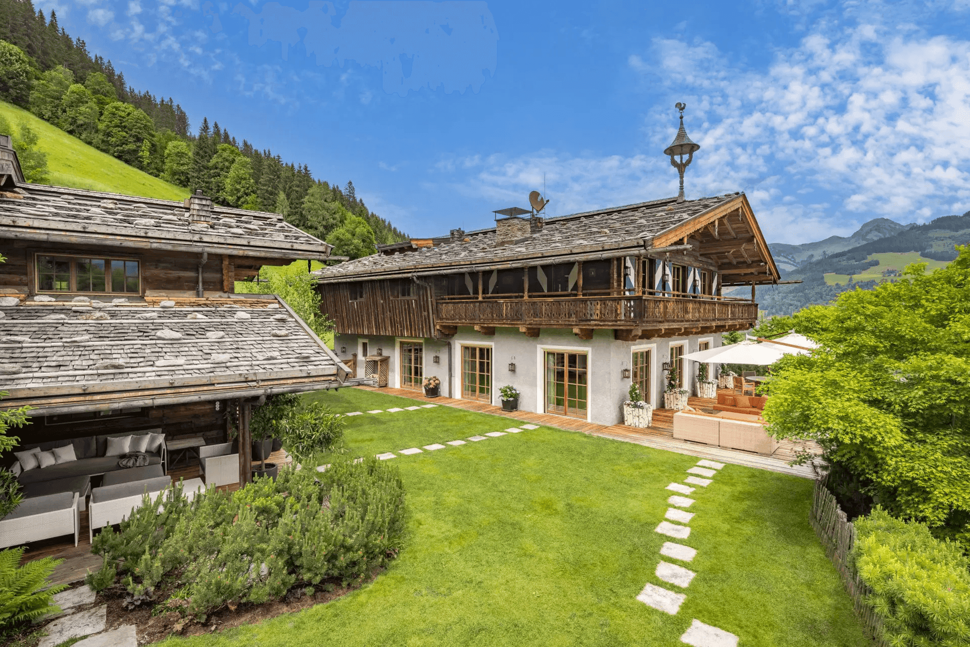Weitläufige Chalet-Anlage mit zwei Gebäuden, großem Garten und beeindruckendem Bergpanorama.