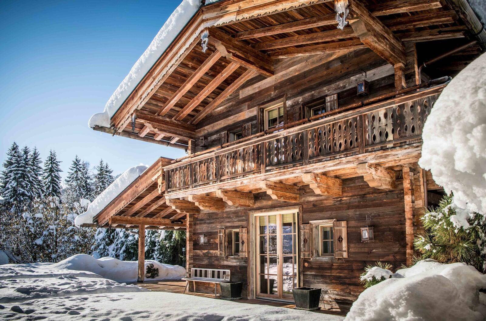 Malerisches Holzchalet im Winter, bedeckt mit Schnee, umgeben von verschneiten Bäumen.
