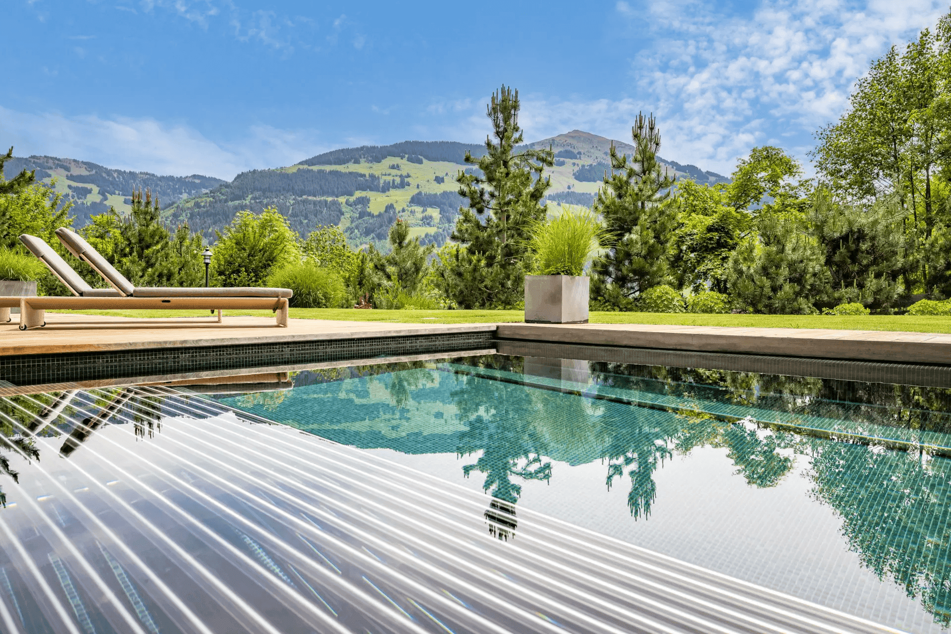 Moderner Außenpool mit Holzdeck und atemberaubendem Blick auf die umliegende Berglandschaft.