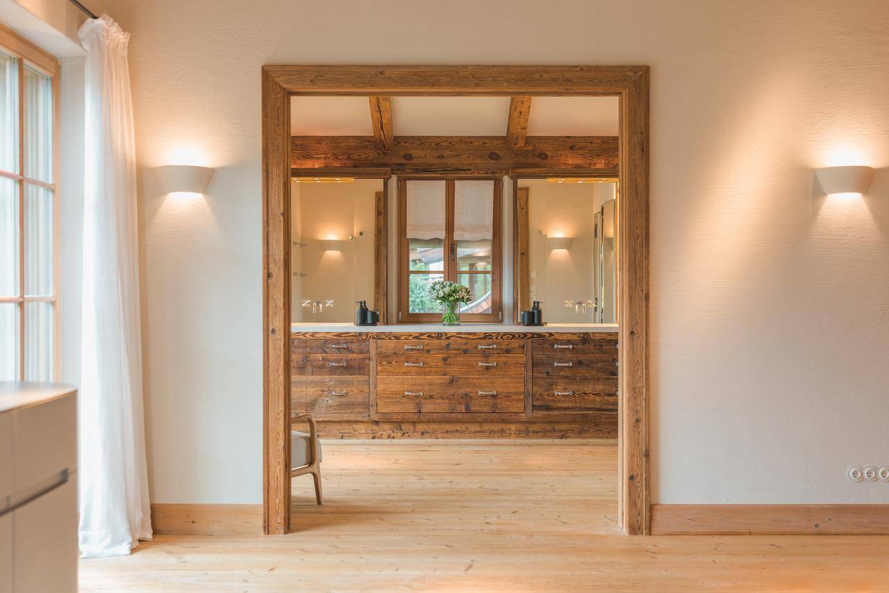 Geräumiges Badezimmer mit rustikalem Holzwaschtisch, Doppelwaschbecken und sichtbaren Deckenbalken.