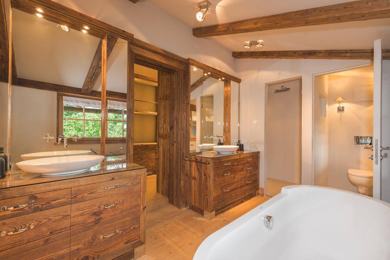 Großes Badezimmer mit zwei Waschtischen, Badewanne und Zugang zu einem begehbaren Kleiderschrank.
