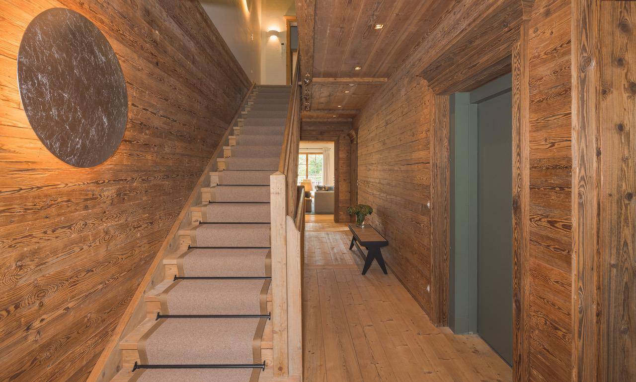 Geräumiger Flur mit Holzvertäfelung, Treppe und Zugang zu einem Aufzug.