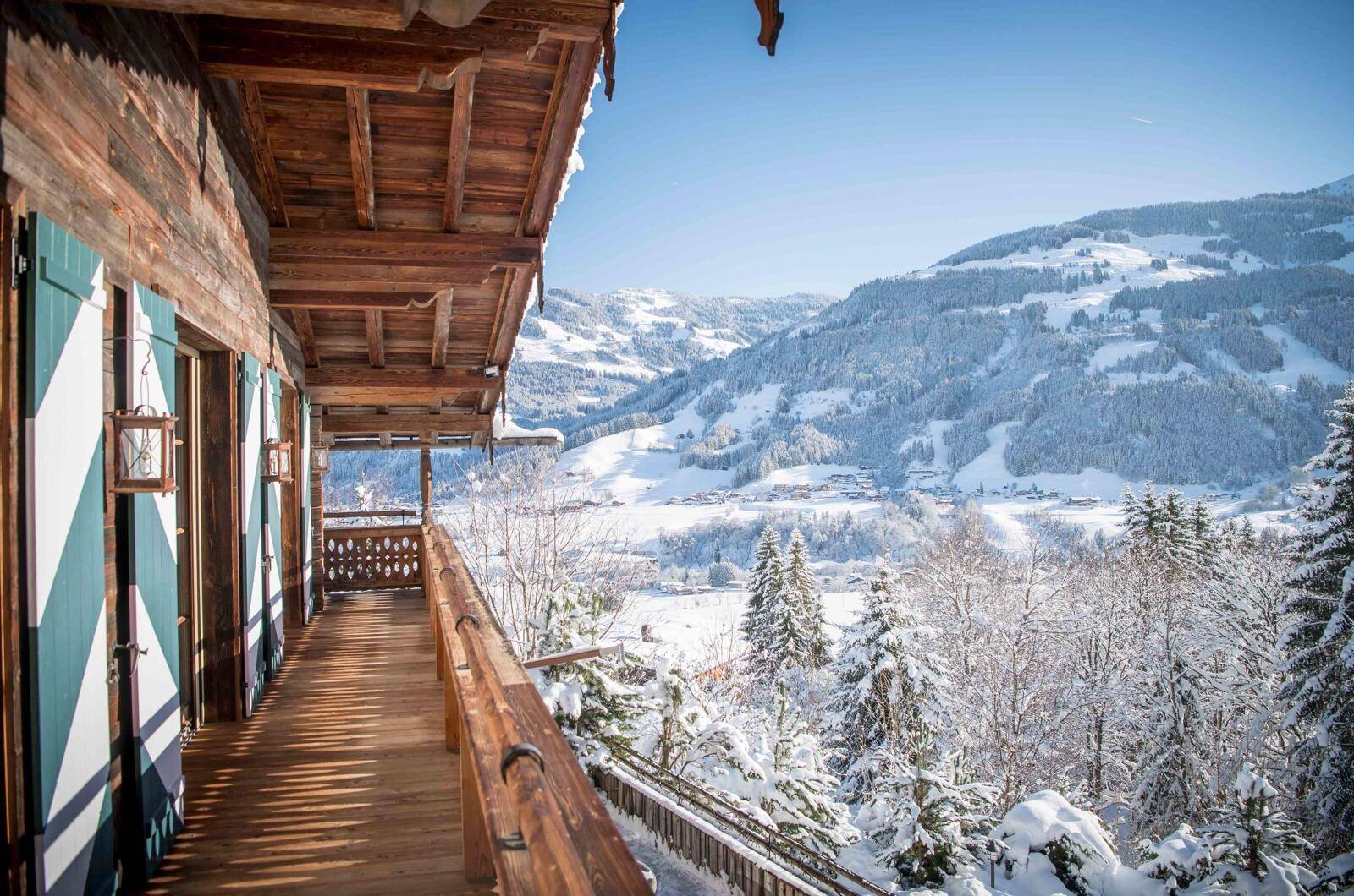 Holzbalkon mit traditionellem Geländer und atemberaubendem Blick auf die verschneite Berglandschaft im Winter.