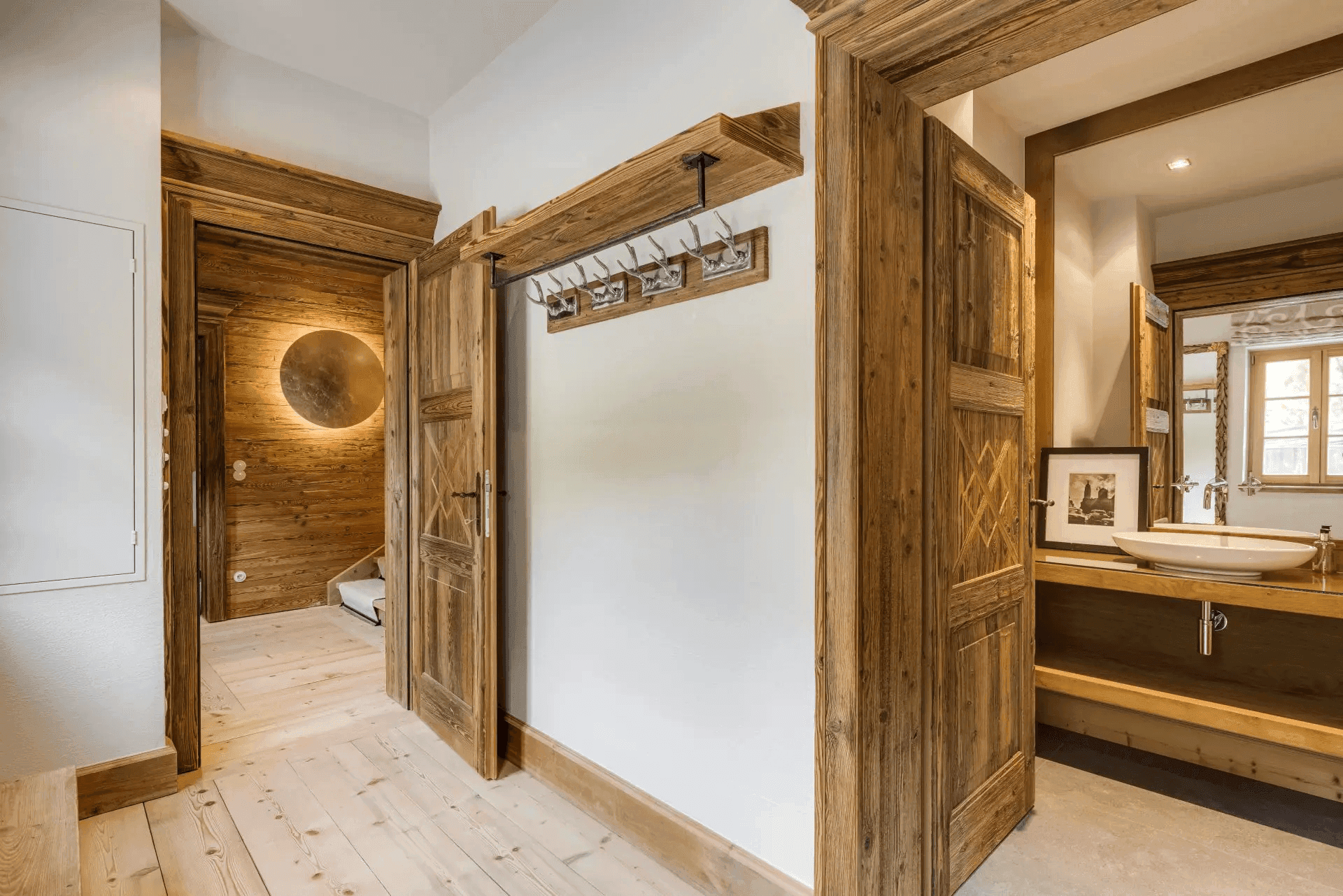 Heller Flur mit Holzboden und Zugang zu einem Badezimmer mit Doppelwaschbecken.