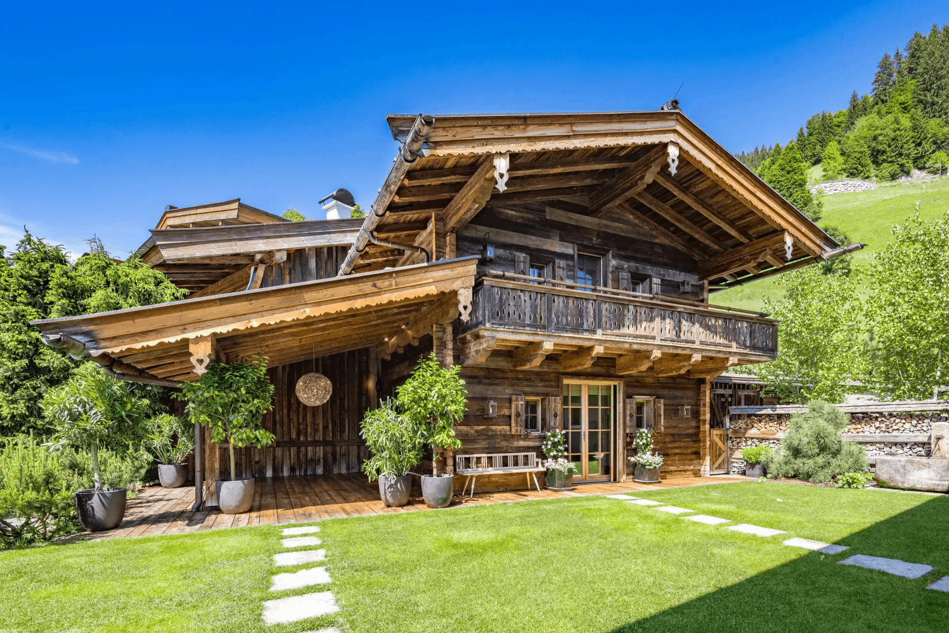 Charmantes Holzchalet mit großzügiger Terrasse, gepflegtem Rasen und üppiger Vegetation.