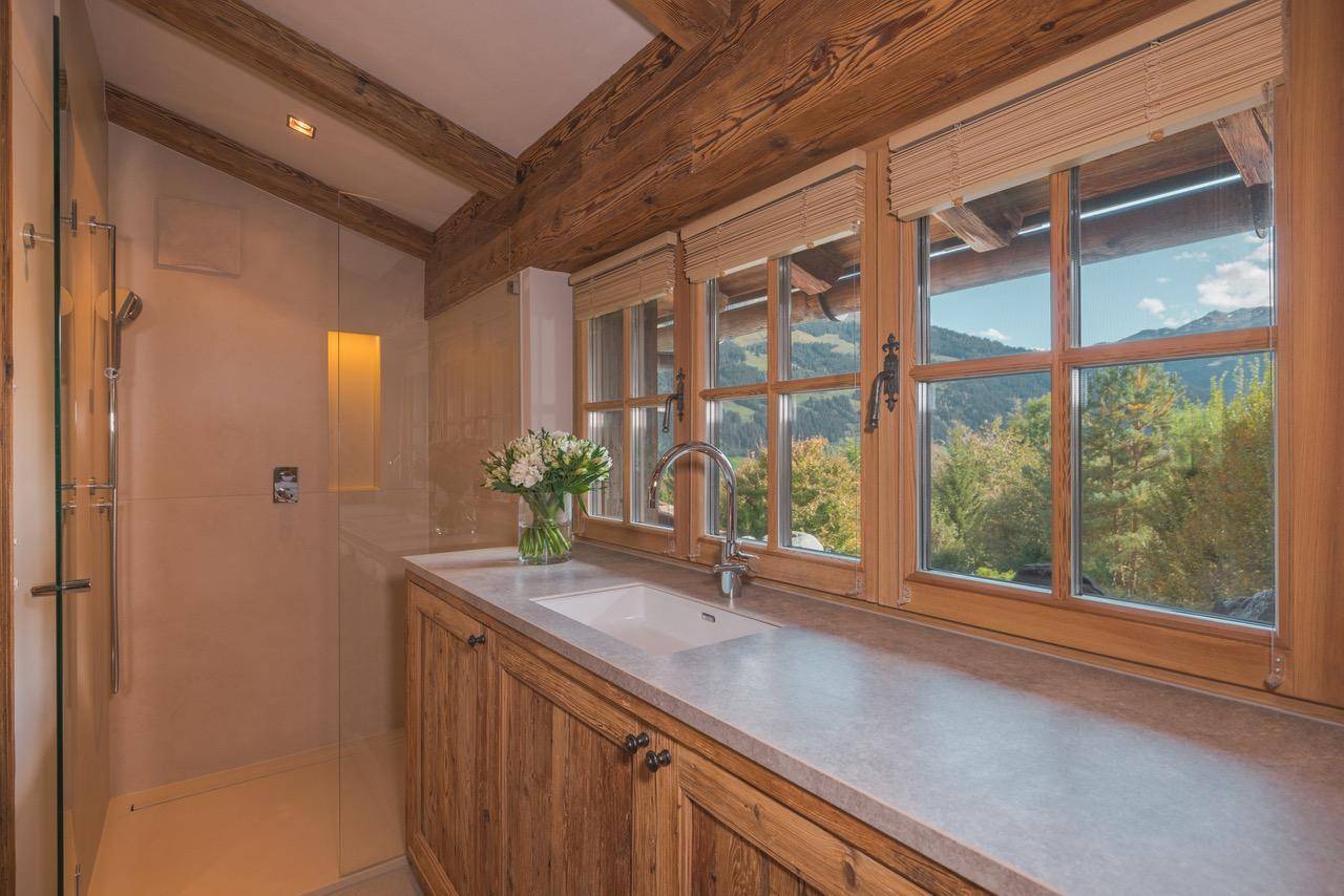 Modernes Badezimmer mit Dusche, Einzelwaschbecken und großem Fenster mit Bergblick.