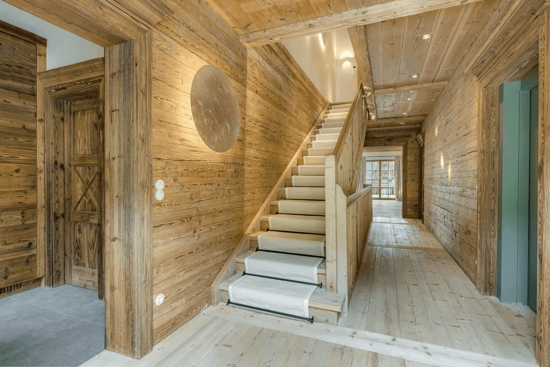 Geräumiger Flur mit Holzvertäfelung, Treppe und modernem Wandlicht.