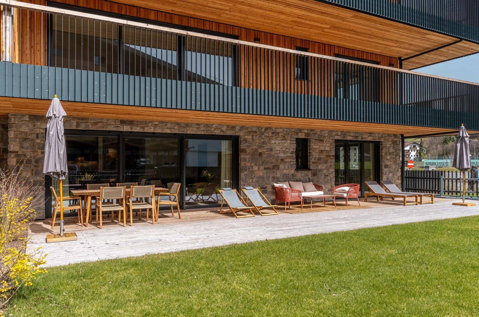 Weitläufige Terrasse mit verschiedenen Sitzbereichen und Sonnenschirmen vor einer Bergkulisse.