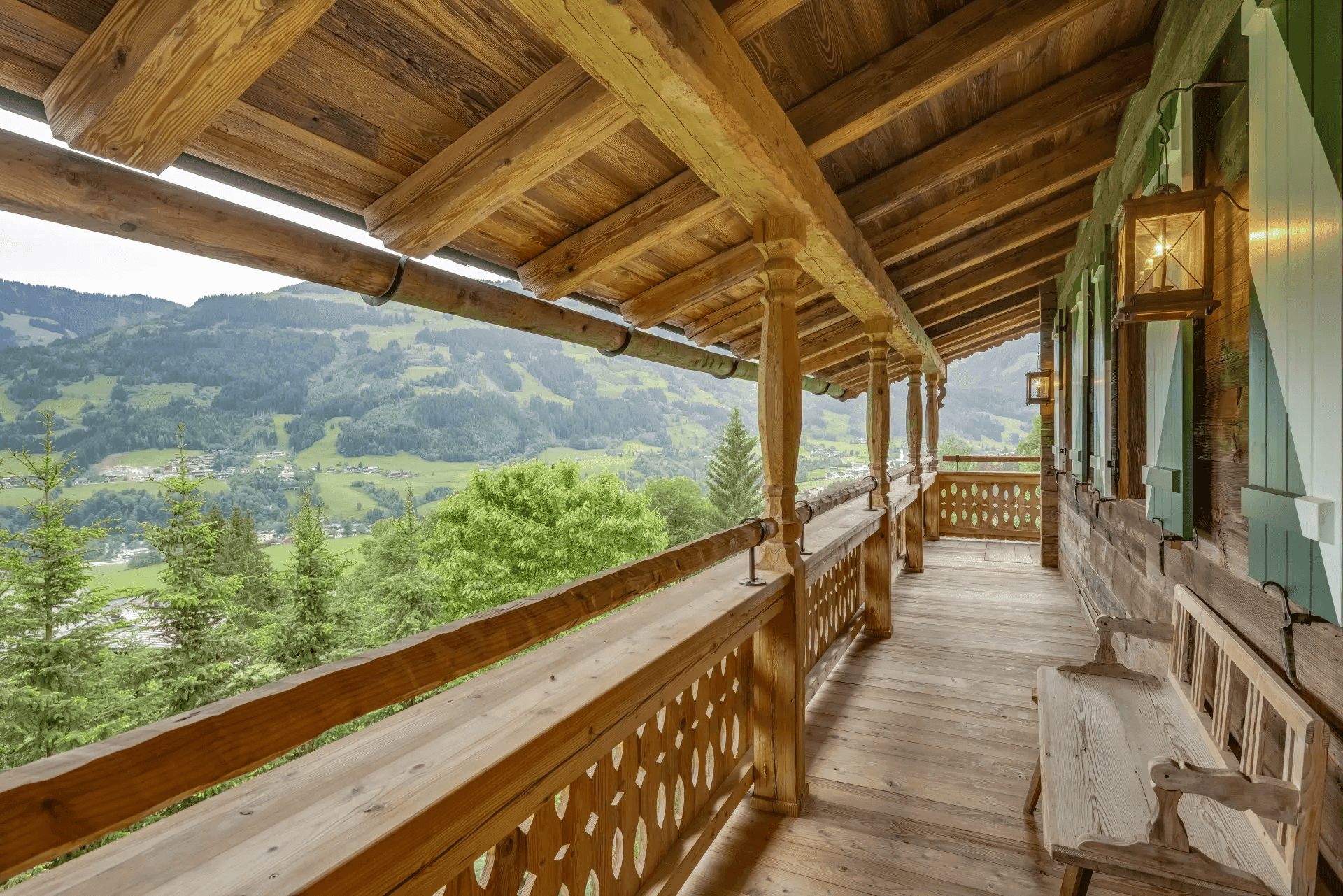 Langer Holzbalkon mit traditionellem Geländer und weitem Blick über das Tal und die Berge.
