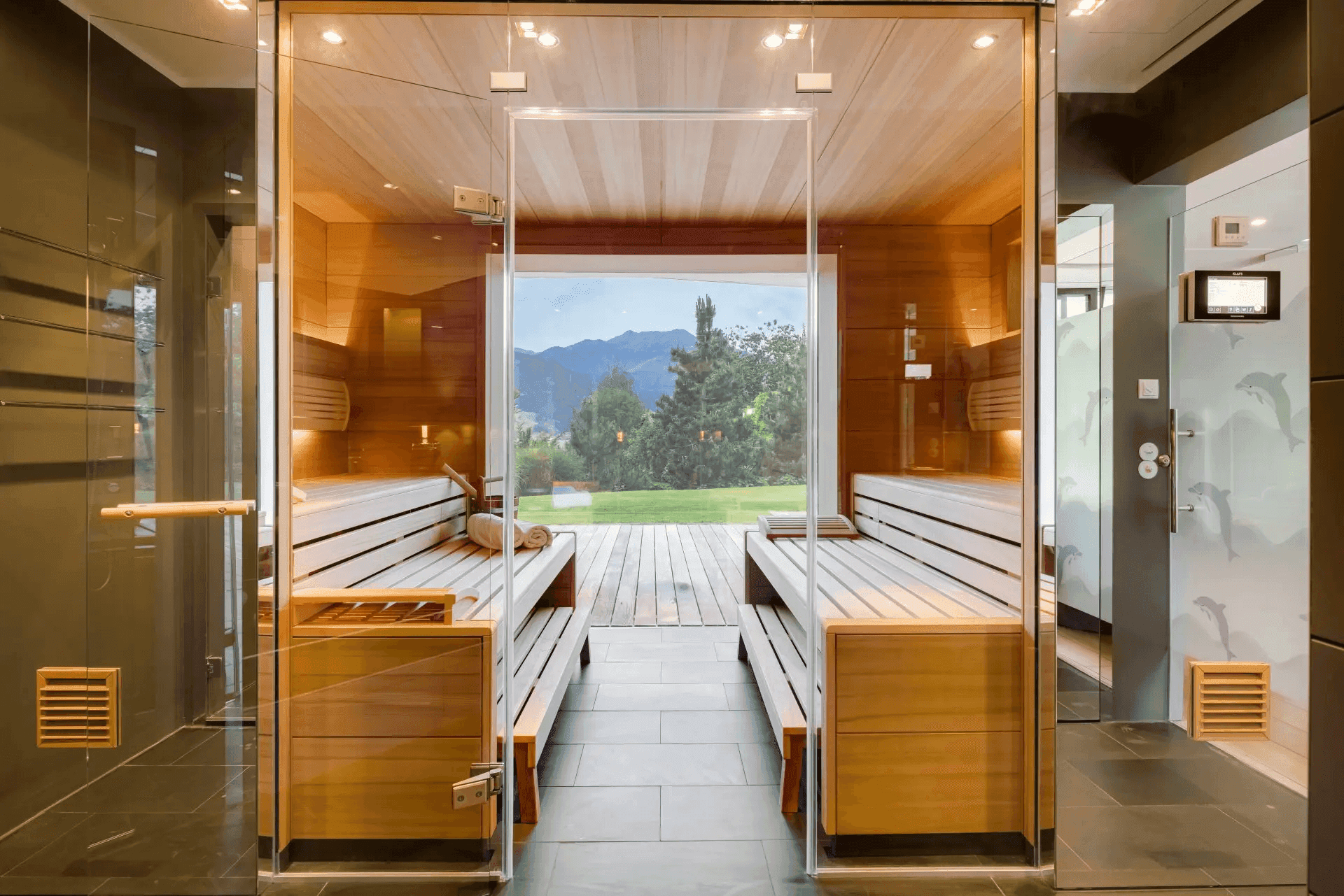 Moderne Sauna mit Holzbänken und großem Fenster mit Blick ins Grüne.