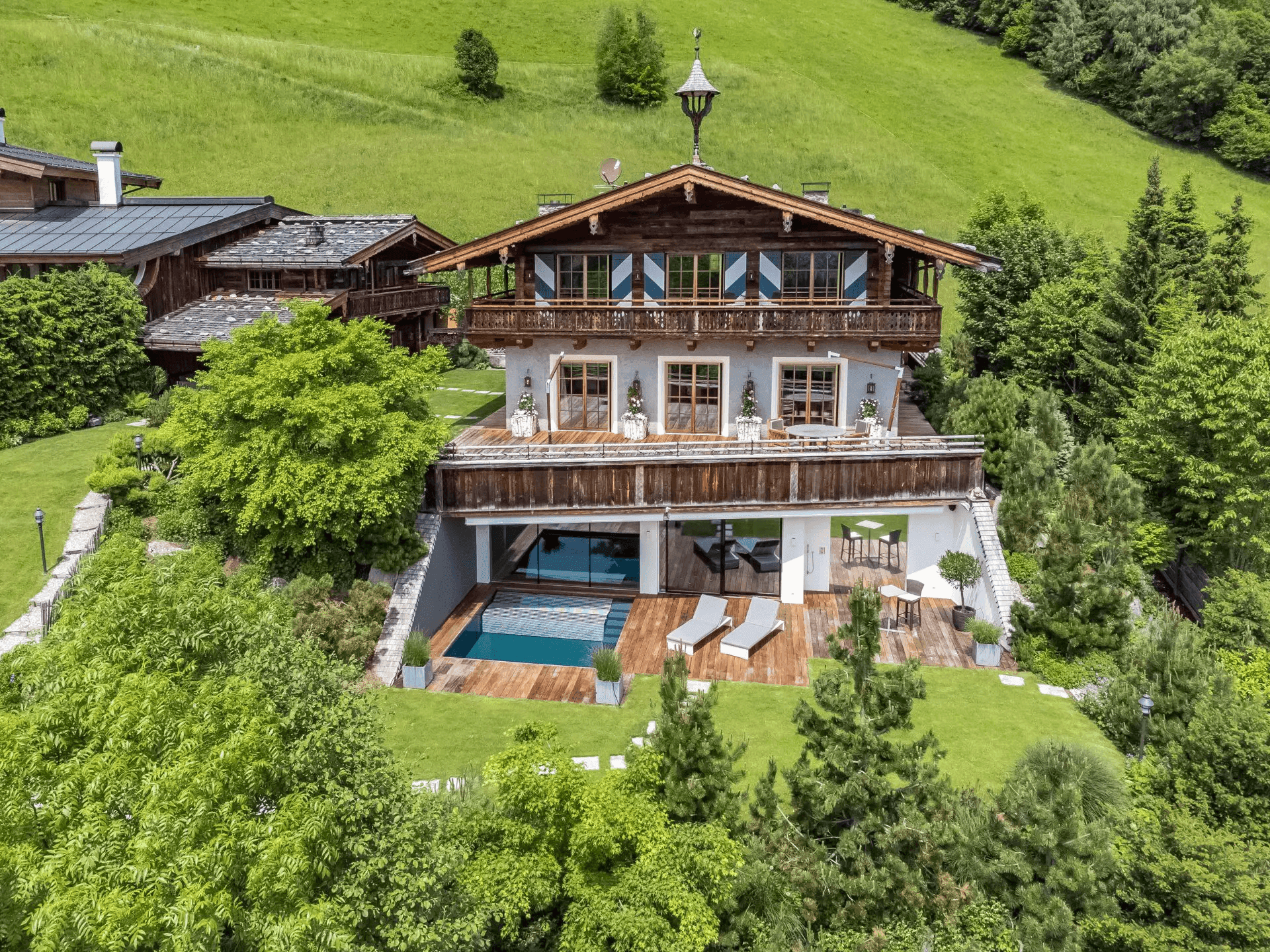 Luftaufnahme des luxuriösen Chalets mit Außenpool, weitläufigem Garten und beeindruckendem Bergpanorama.