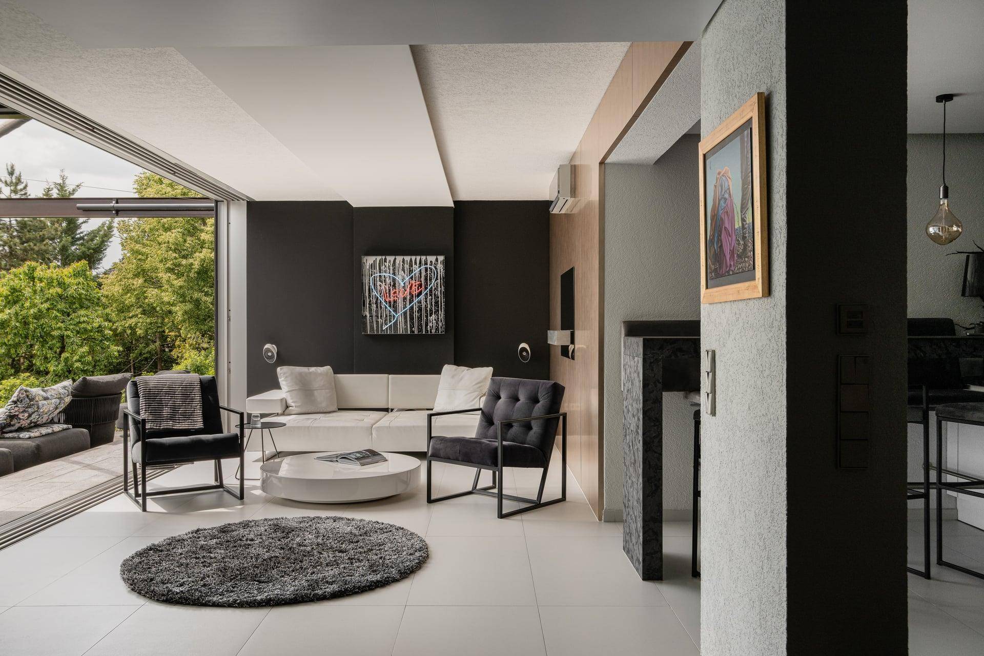 Stilvolles Wohnzimmer mit dunklen Wänden, weißen Möbeln und Zugang zu einer Außenterrasse.