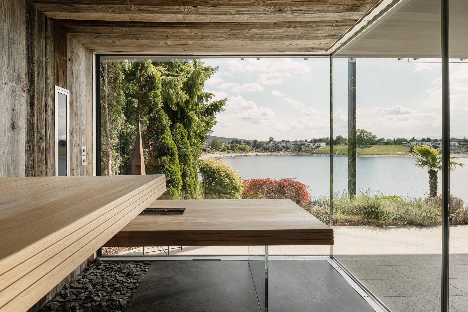 Moderne Sauna mit Holzbänken und raumhohen Fenstern, die einen weiten Blick bieten.