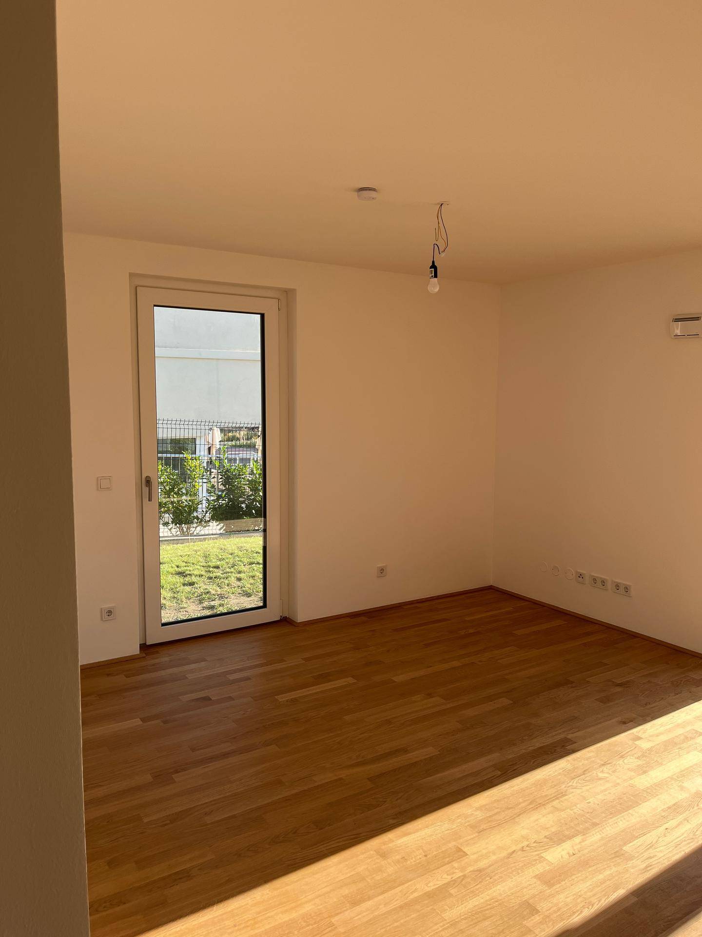 Helles Zimmer mit Parkettboden und Zugang zum Garten, bereit für individuelle Gestaltung.