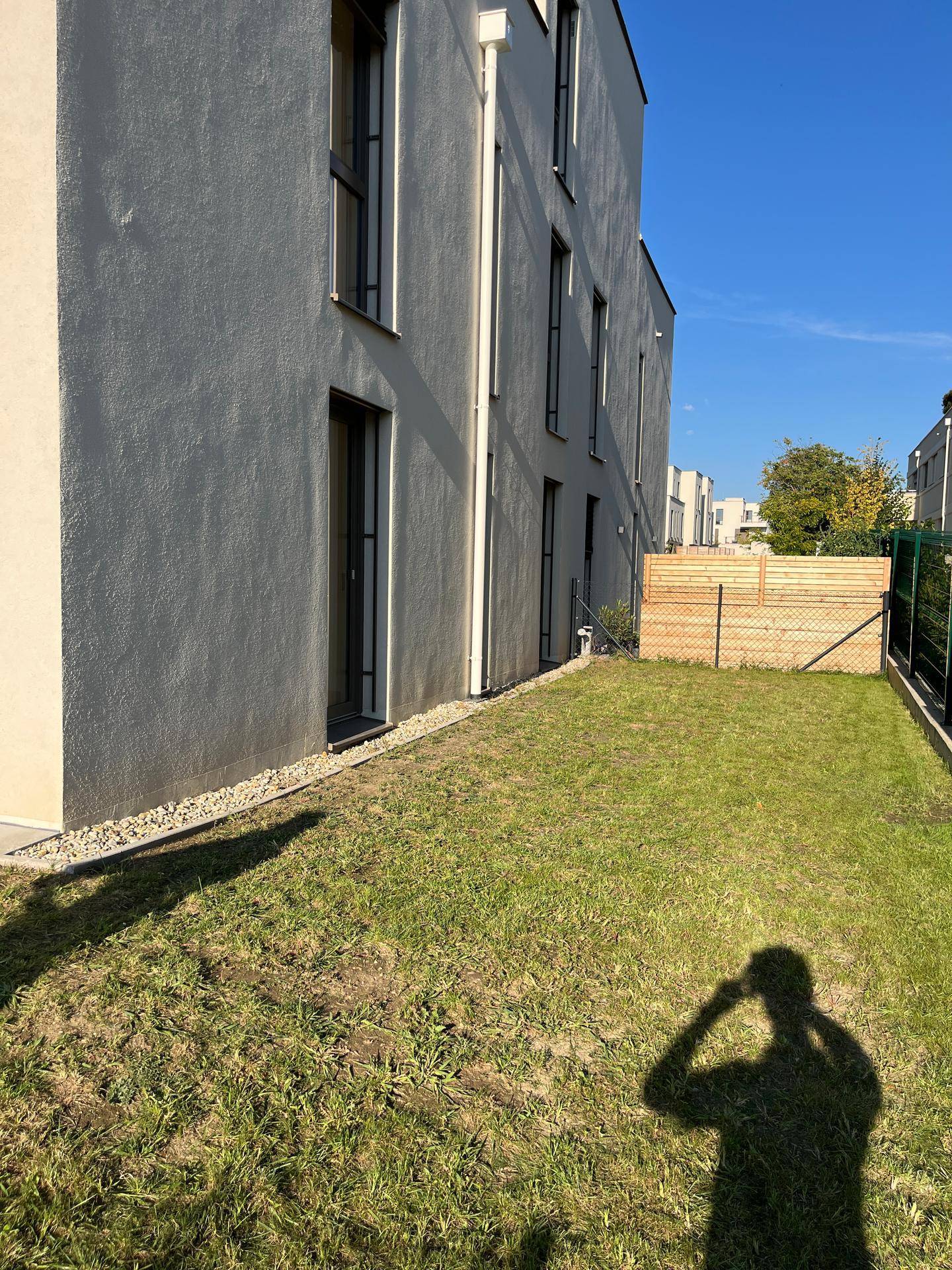 Seitlicher Gartenbereich mit Rasenfläche und Holzzaun, bietet Privatsphäre im Freien.