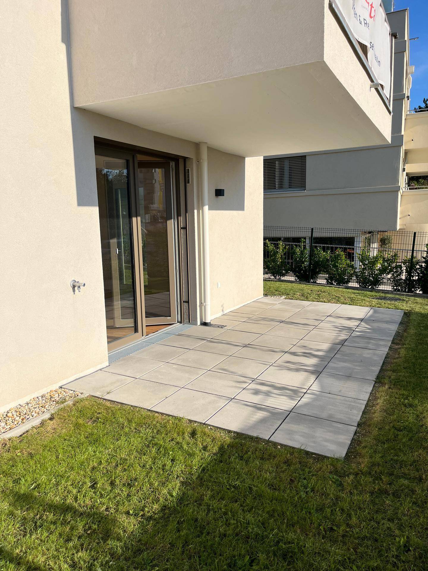 Geräumige Terrasse mit Fliesenboden und direktem Zugang zur privaten Grünfläche.