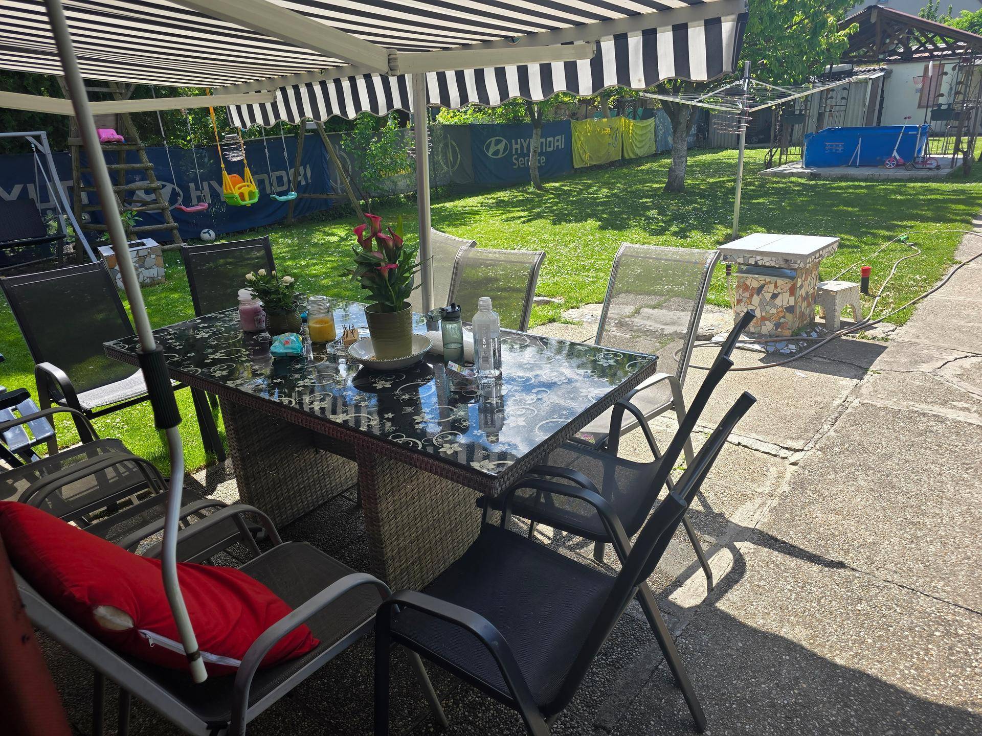 Überdachte Terrasse mit Esstisch und Stühlen, Blick auf den Garten.