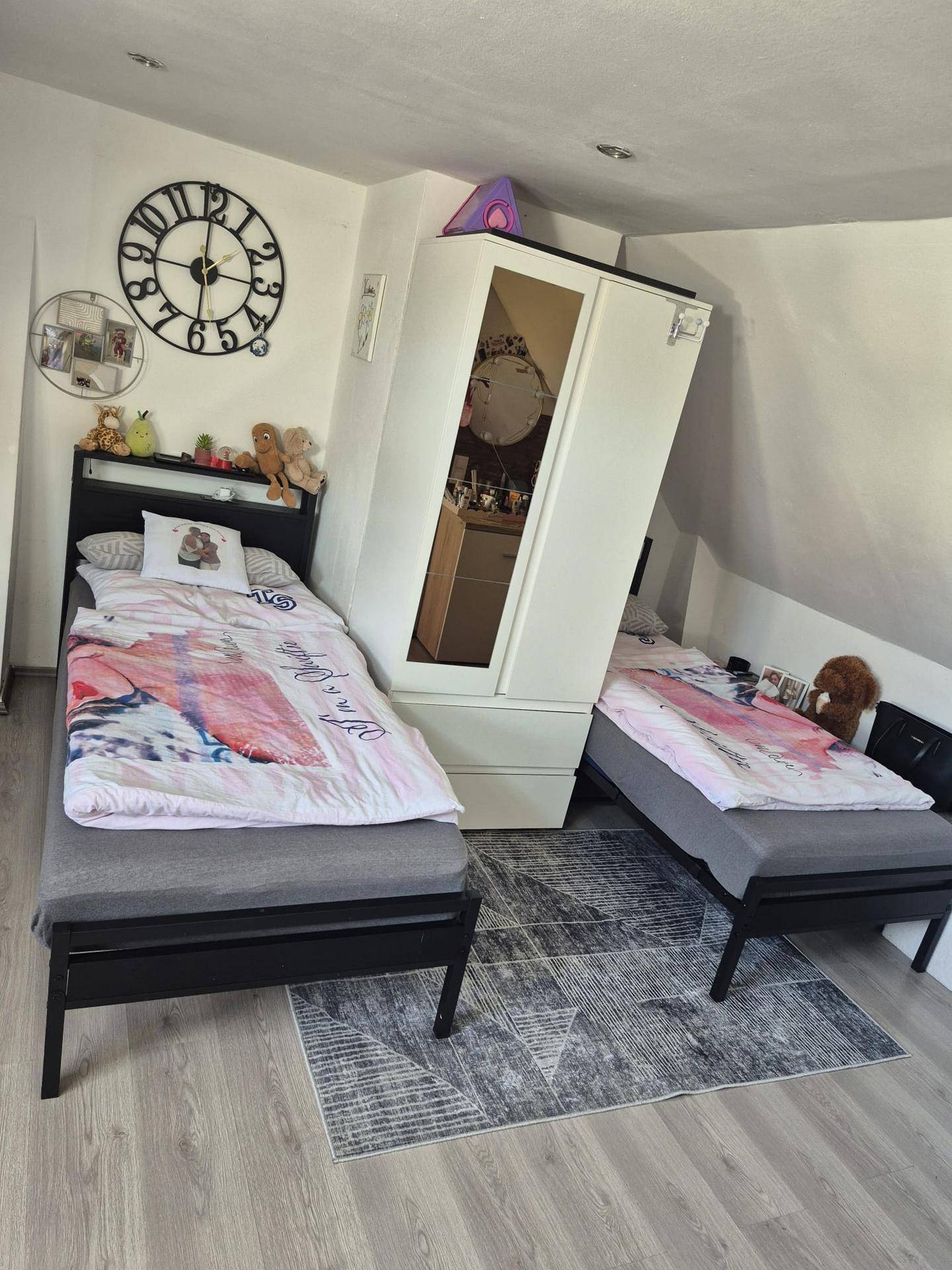 Kinderzimmer im Dachgeschoss mit zwei Einzelbetten, Teppich und schräger Decke.