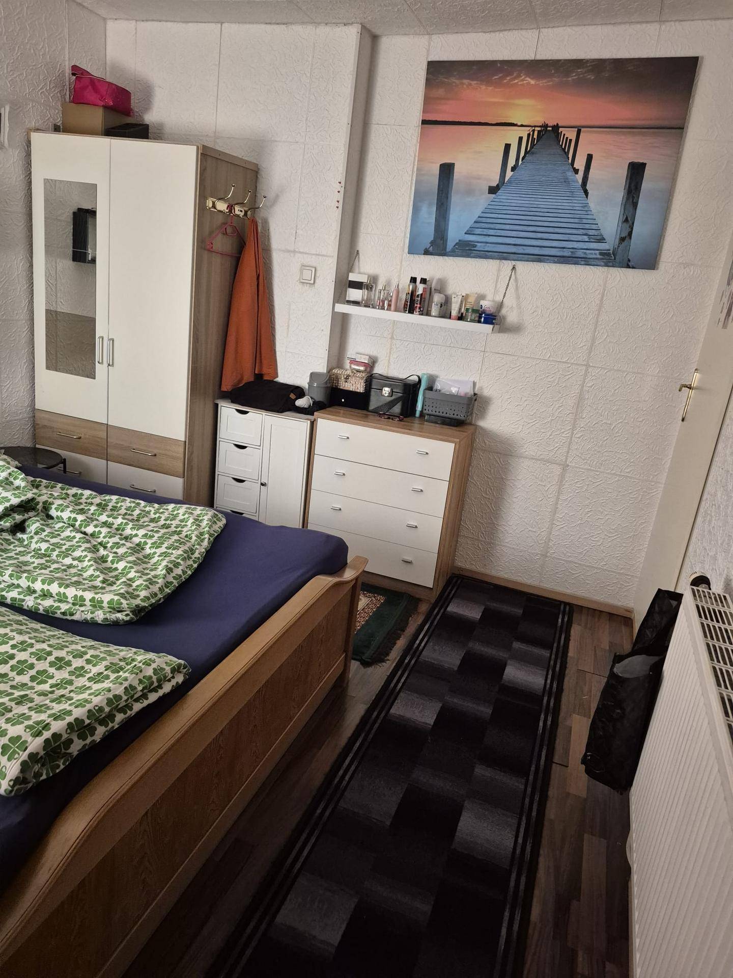 Schlafzimmer mit Doppelbett, Kommoden und einem großen Wandbild über dem Bett.
