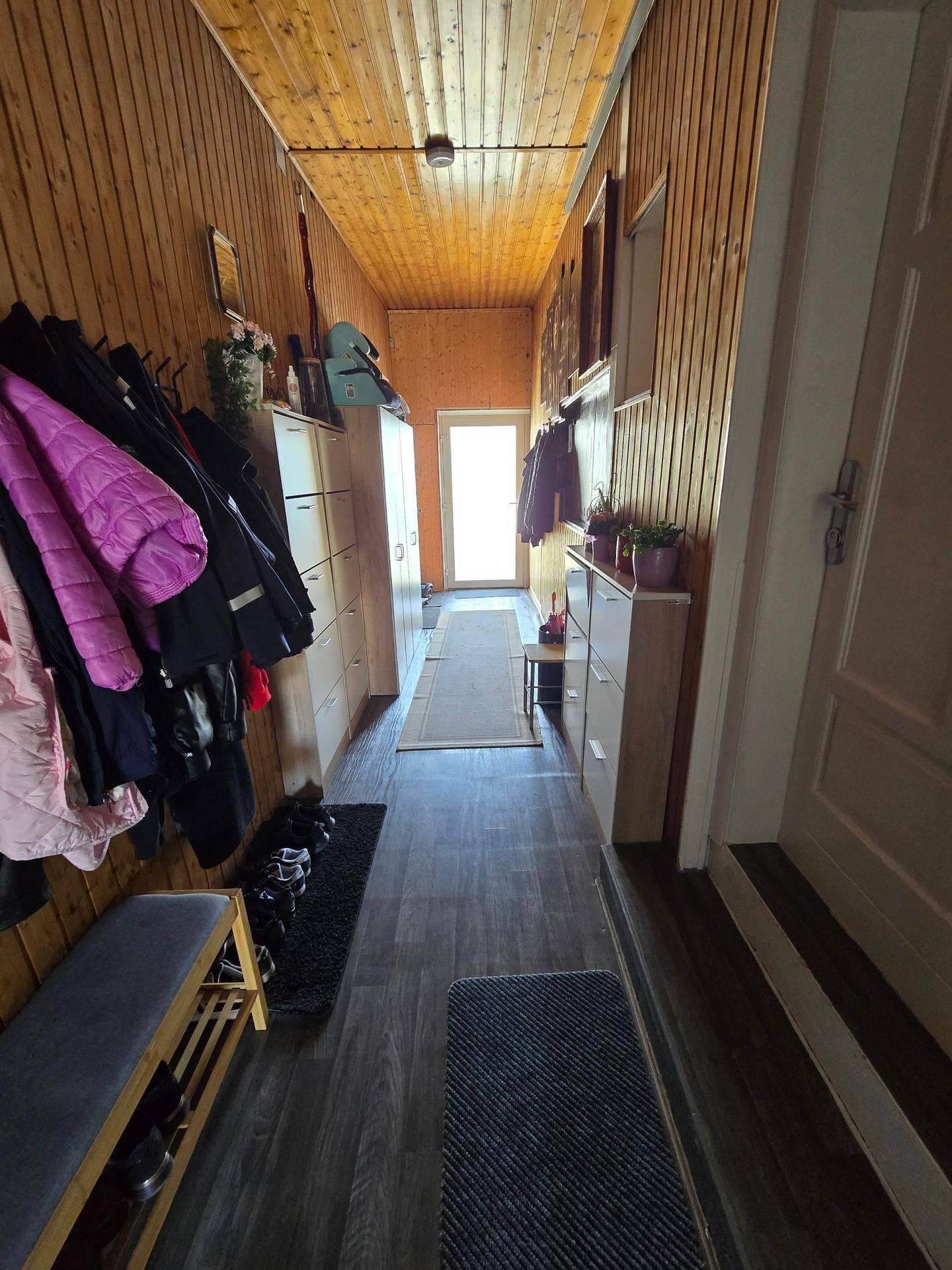 Gemütlicher Flur mit Holzverkleidung, praktischen Schuhschränken und dunklem Laminatboden.