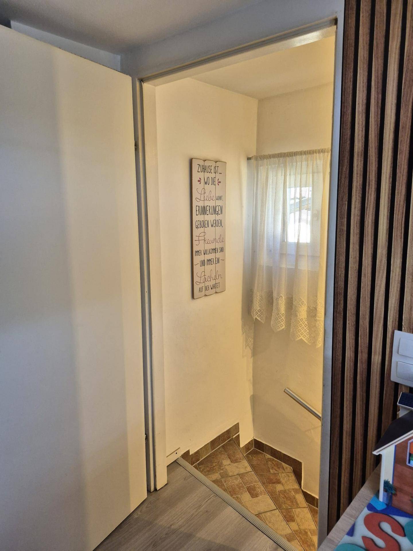 Heller Flur mit Treppenabgang und einem Fenster, das natürliches Licht hereinlässt.