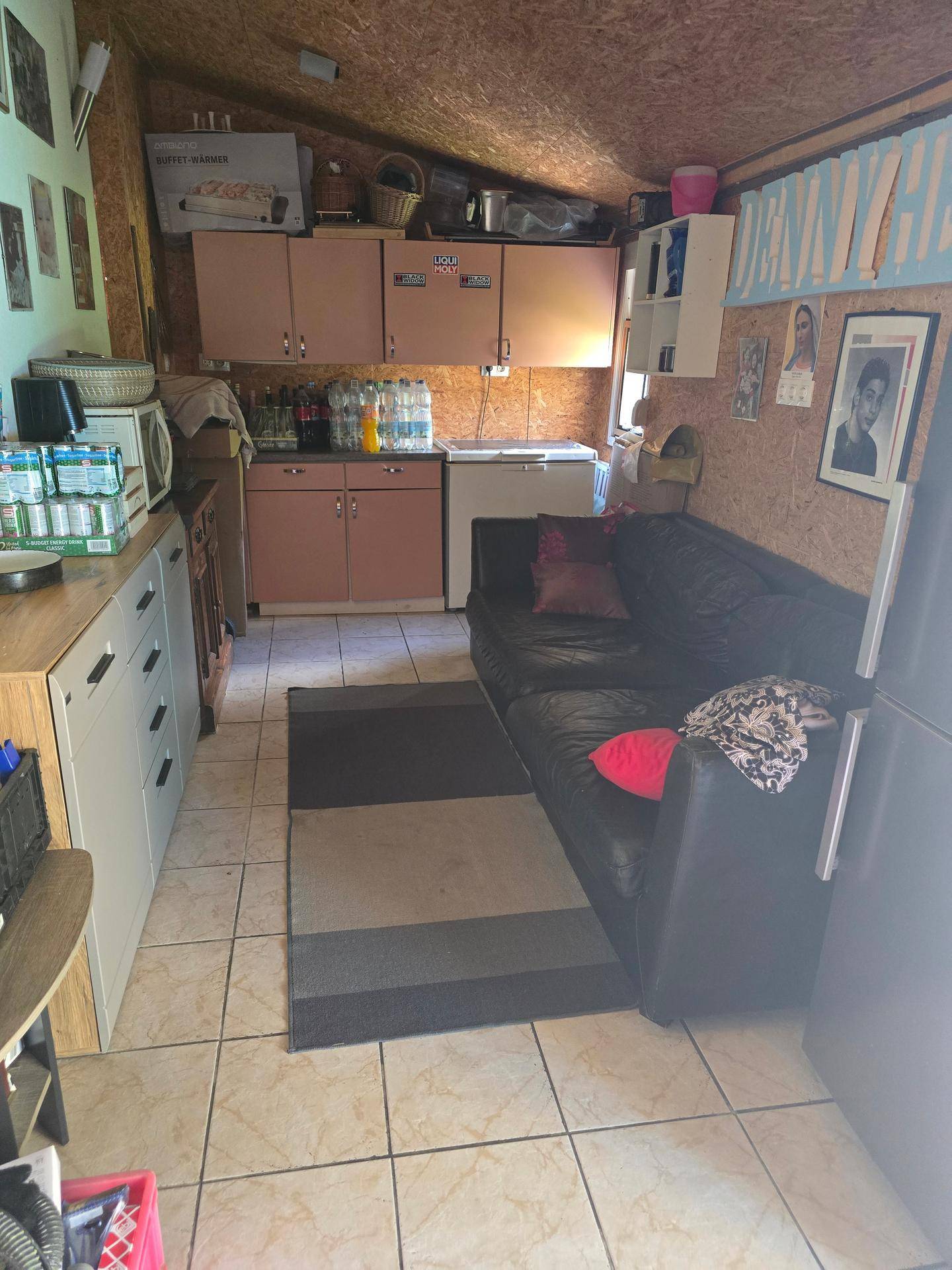 Rustikaler Mehrzweckraum mit kleiner Küchenzeile, Sofa und Fliesenboden.