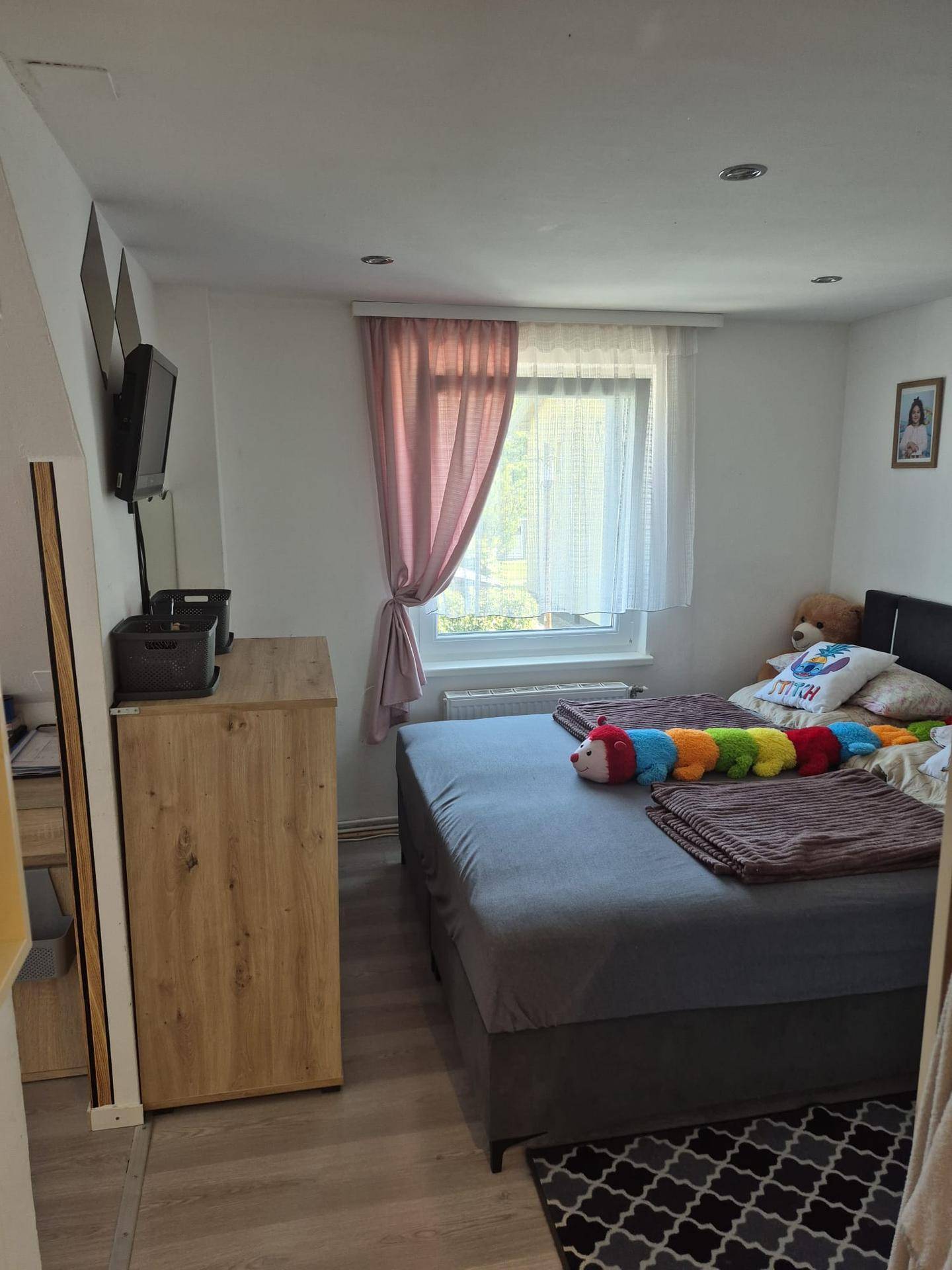 Helles Schlafzimmer mit Doppelbett, Fenster und modernem Holzschrank.