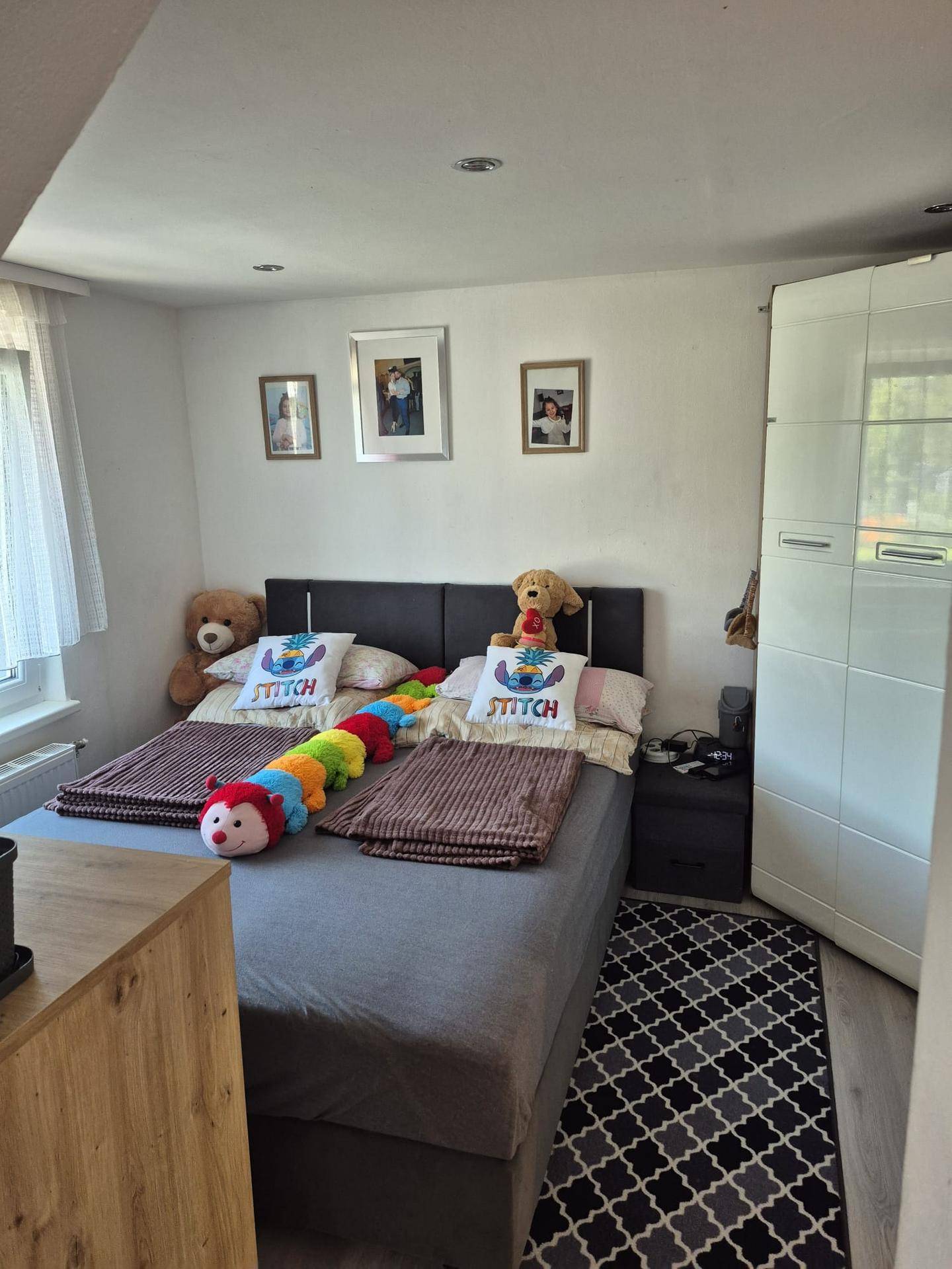 Gemütliches Schlafzimmer mit Doppelbett, Teppich und weißem Kleiderschrank.