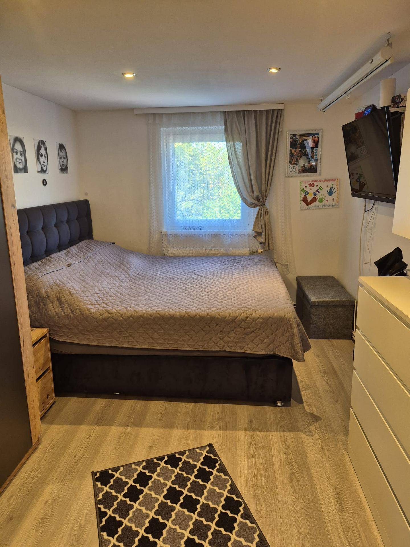 Schlafzimmer mit großem Bett, Fenster und modernem Teppichboden.