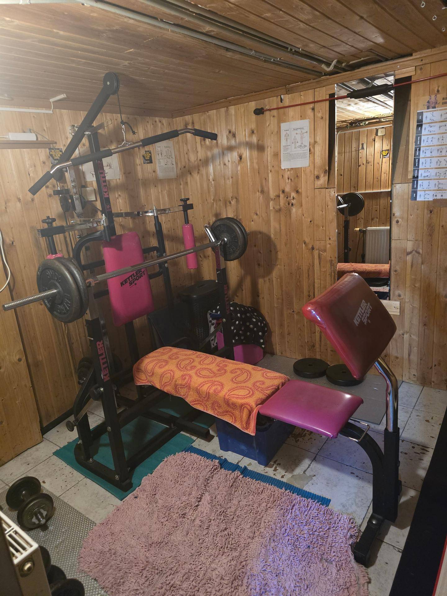 Fitnessraum im Keller mit verschiedenen Trainingsgeräten und Holzverkleidung.