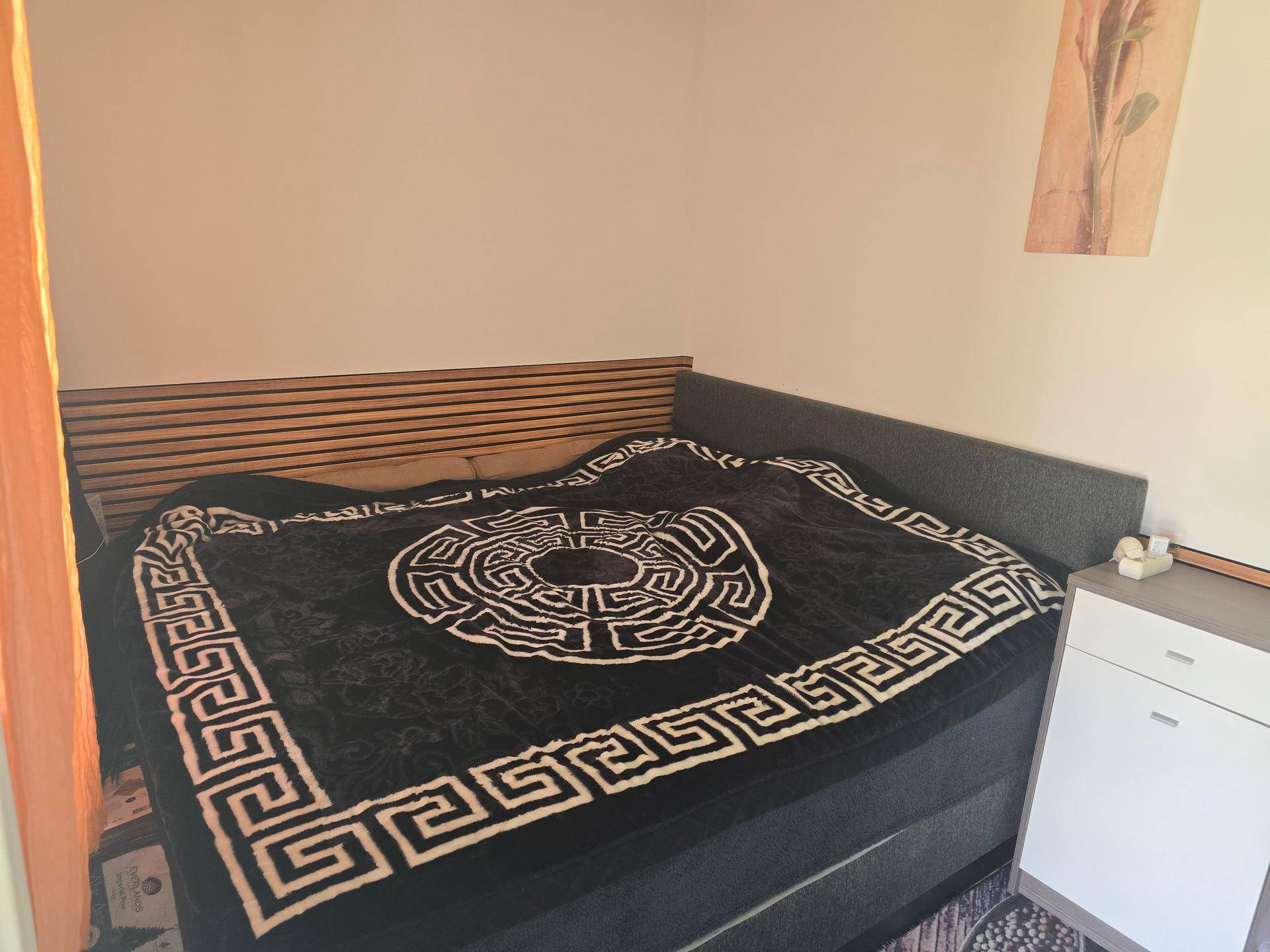 Gemütliches Schlafzimmer mit großem Bett, Holzkopfteil und Nachttisch.