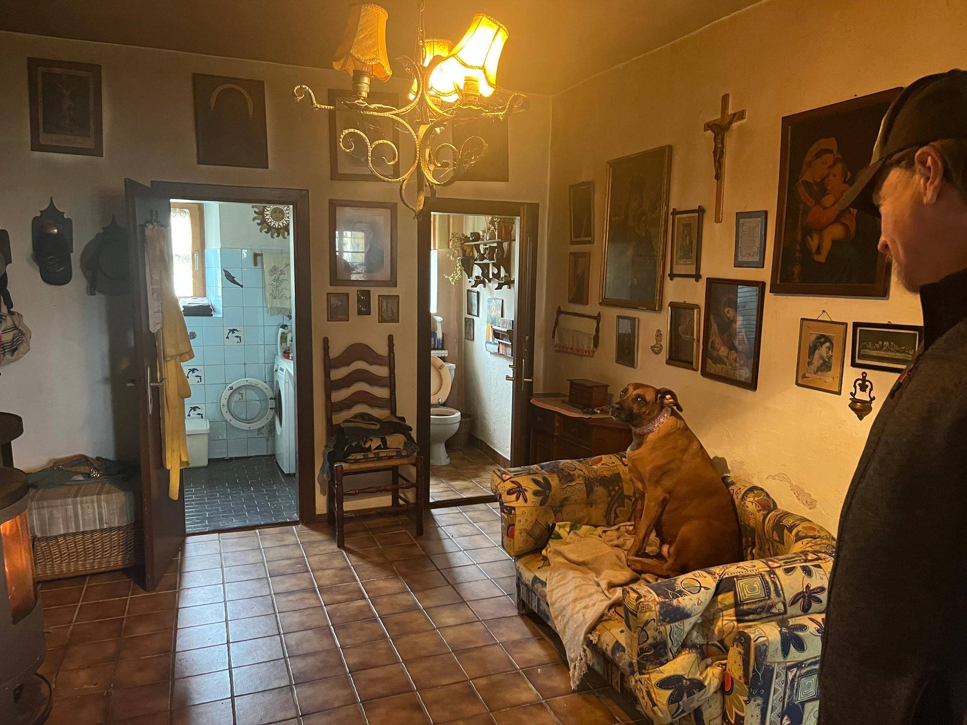 Wohnzimmer mit Fliesenboden, Kaminofen und Blick in ein gefliestes Badezimmer, traditionell eingerichtet.