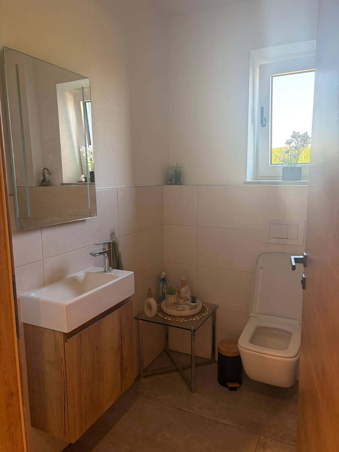 Kleines Gäste-WC mit modernem Waschbecken, Toilette und Fenster für Tageslicht.