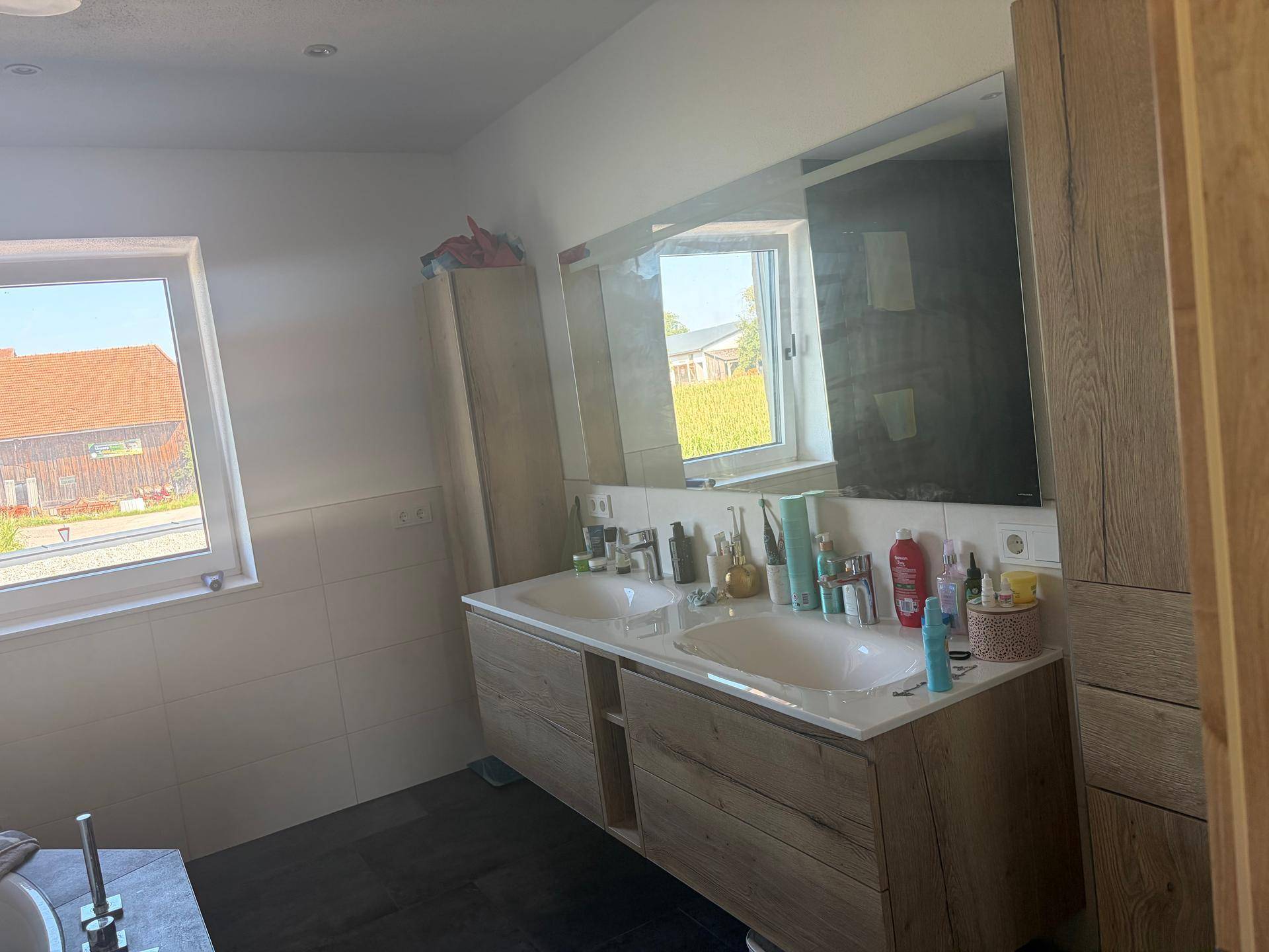 Modernes Badezimmer mit Doppelwaschbecken, großem Spiegel und Fenster mit Weitblick.