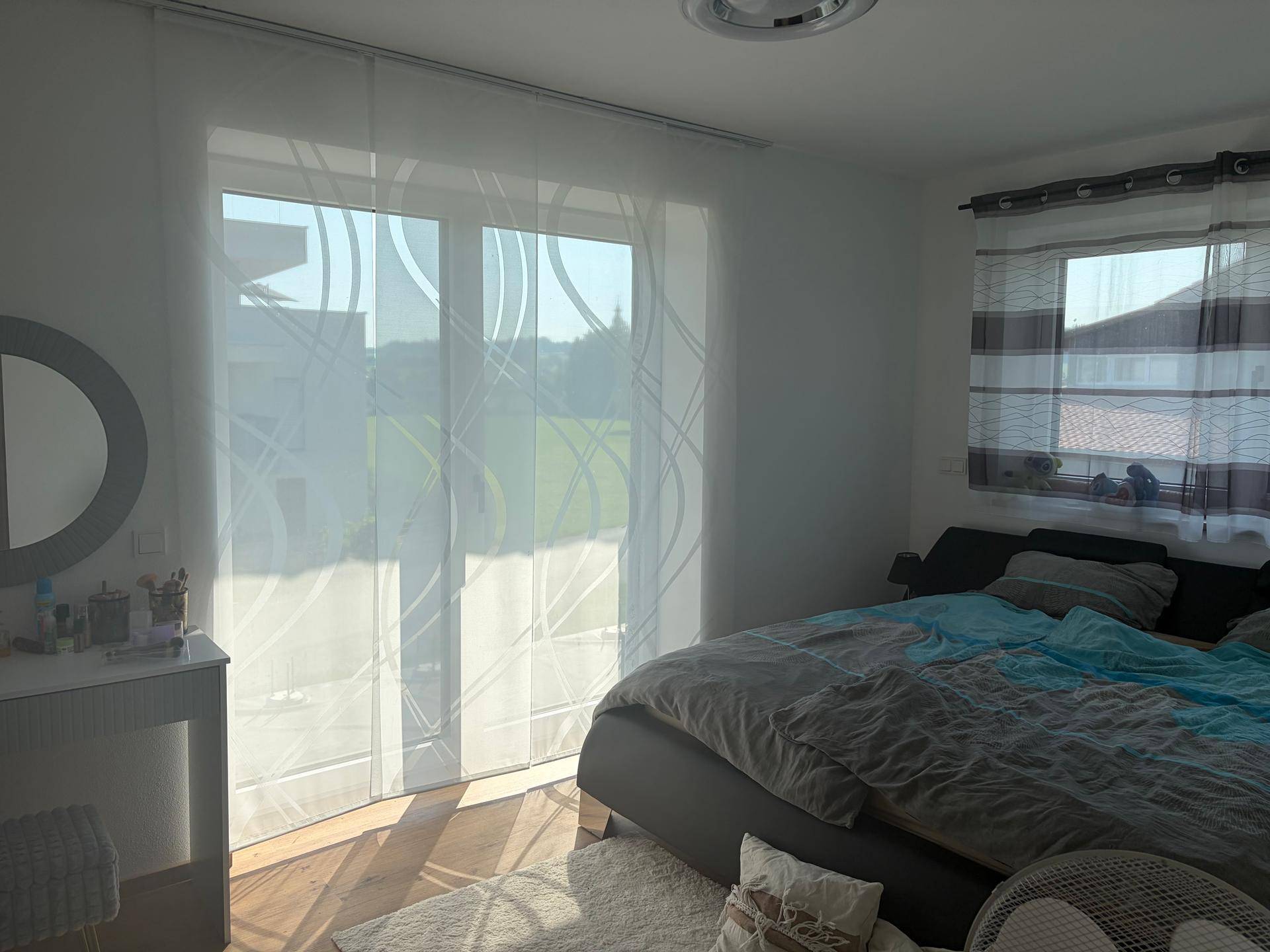 Helles Schlafzimmer mit großem Bett, Holzboden und Zugang zu einem Außenbereich.
