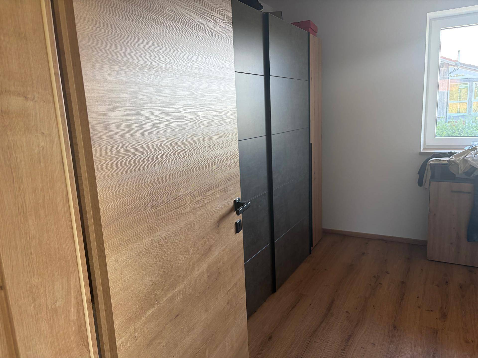 Schlafzimmer mit Holzboden und einem großen Kleiderschrank, der viel Stauraum bietet.