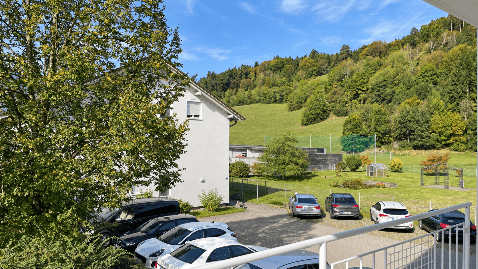 Weitläufiger Blick von einem Balkon auf eine grüne Hügellandschaft und den Außenbereich.
